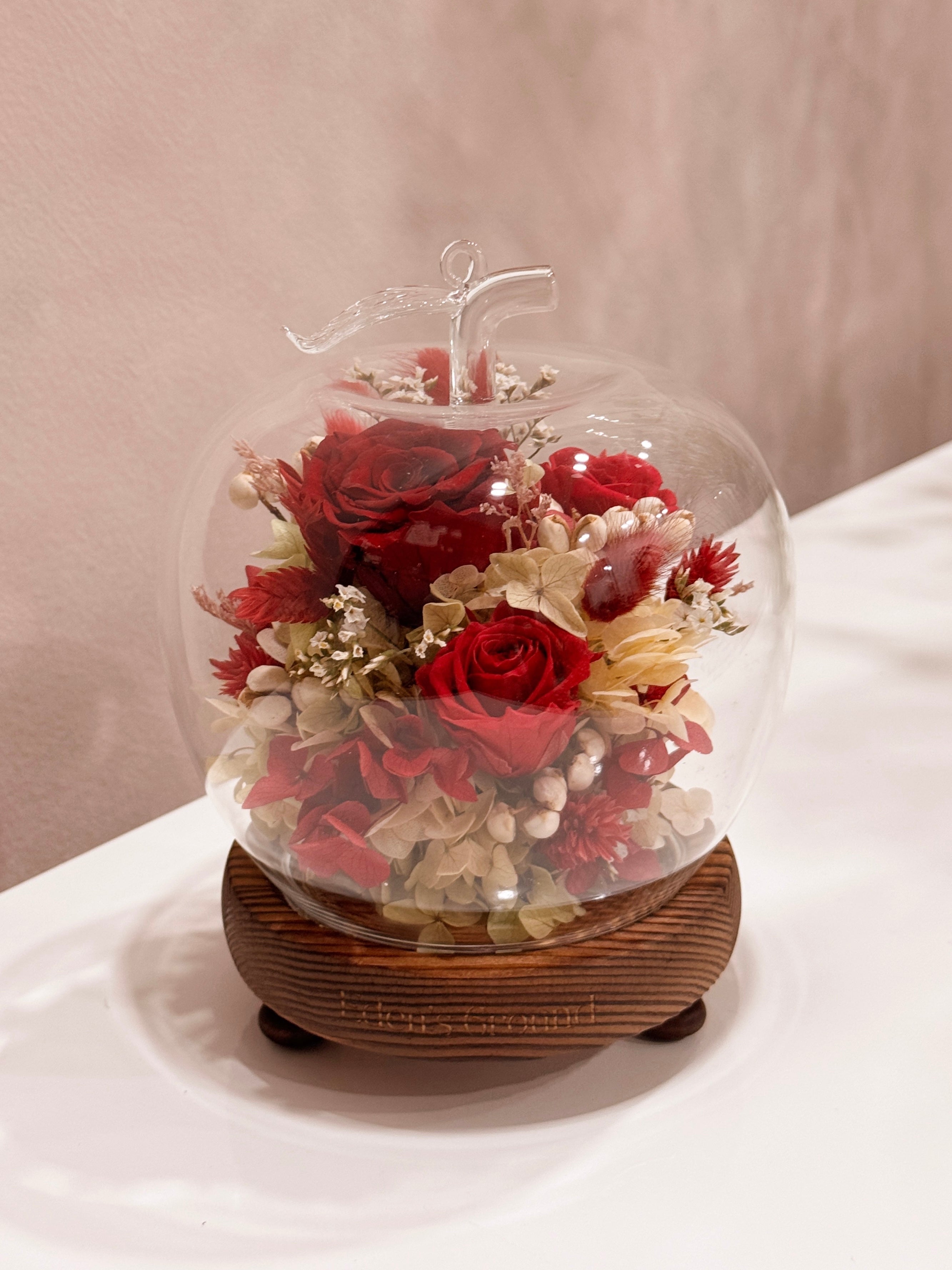 Preserved and dried flowers in a classic red and green palette, artfully arranged in a lighted apple-shaped glass dome by Eden’s Ground—perfect for gifting lasting love this Valentine’s Day.