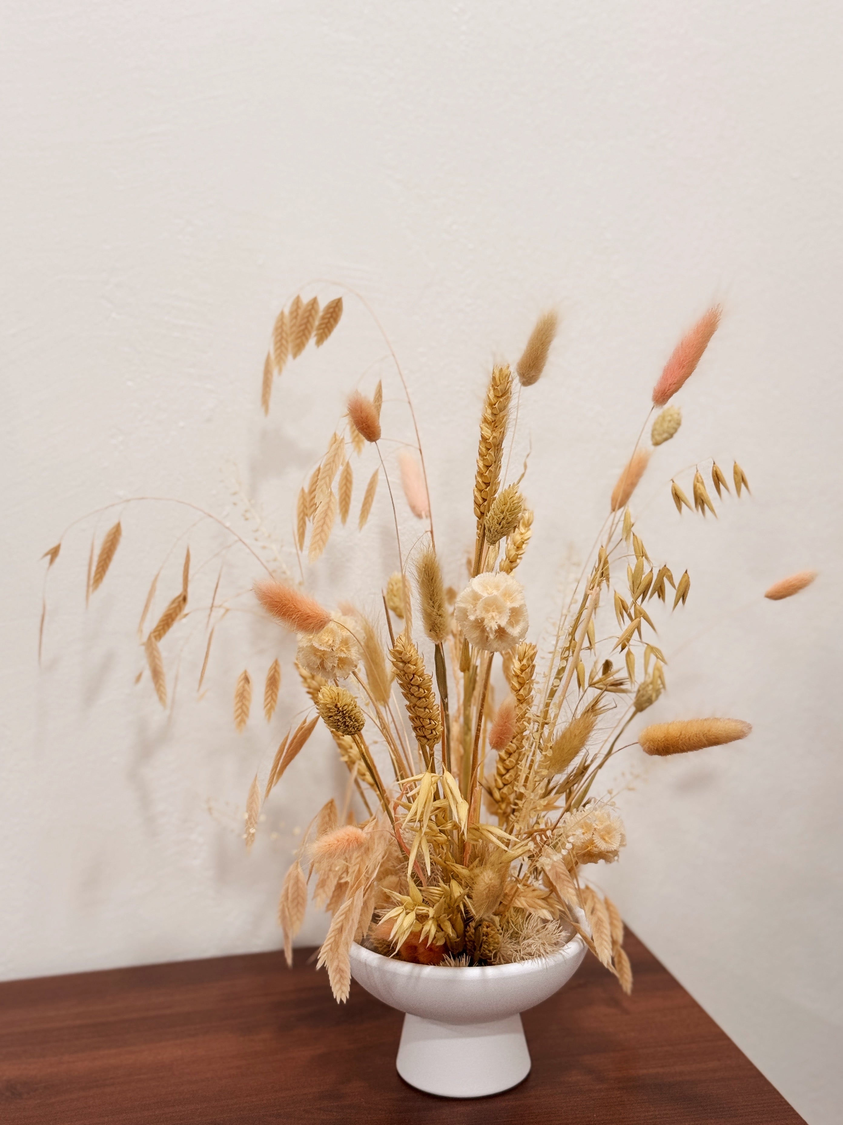 Blushing Prairie vase arrangement, an airy floral arrangement featuring preserved bunny tails, rye, wheat, and a medley of textured natural foliage—artfully styled in a low vase, thoughtfully crafted by Eden’s Ground.