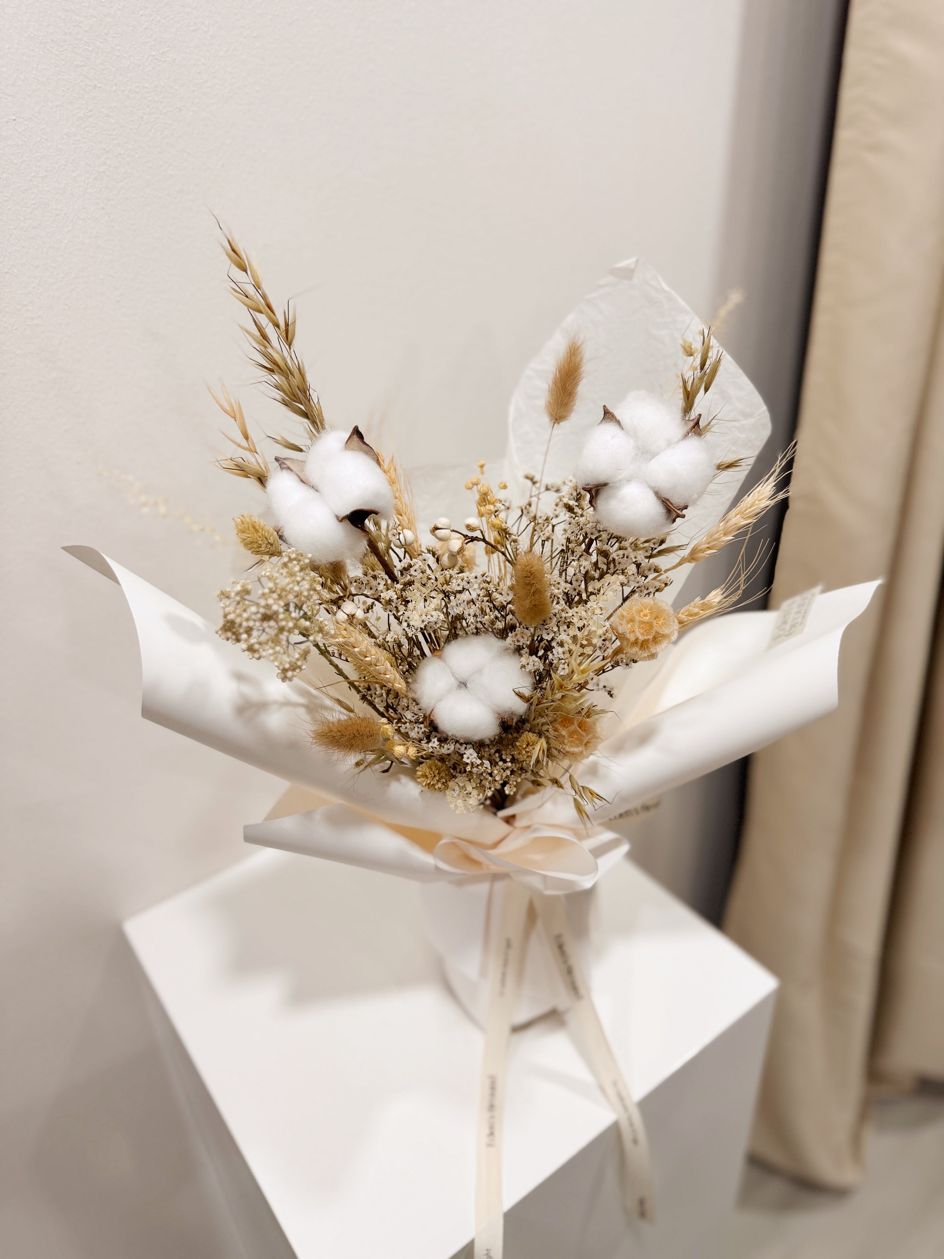 Soft Cotton bouquet made with cotton along with filler flowers and foliage, wrapped in white paper crafted by Eden’s Ground, a floral design boutique.