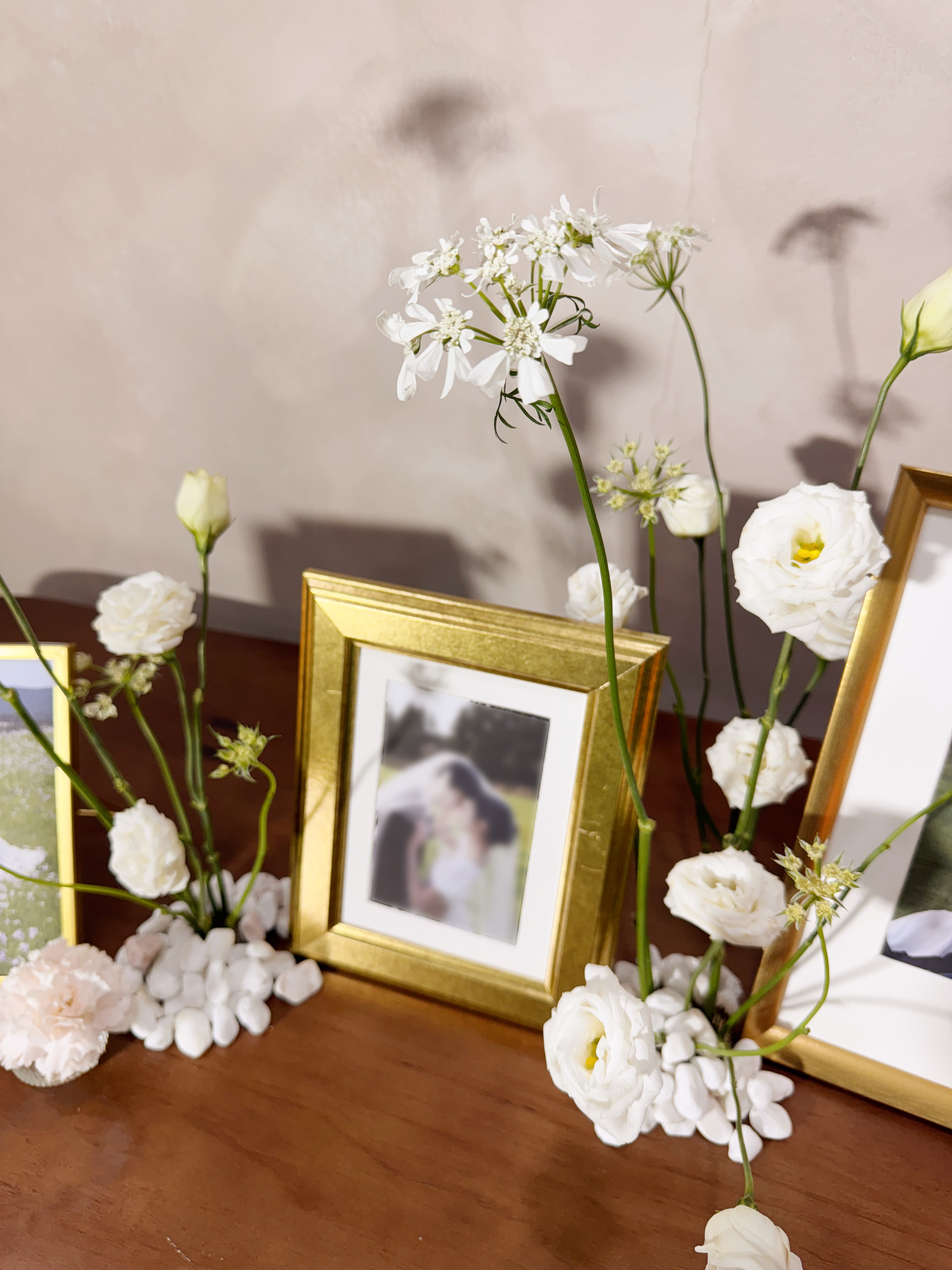 Wedding reception table setting with framed photos, candles, and flowers. Styled by Eden's Ground, a floral design boutique.