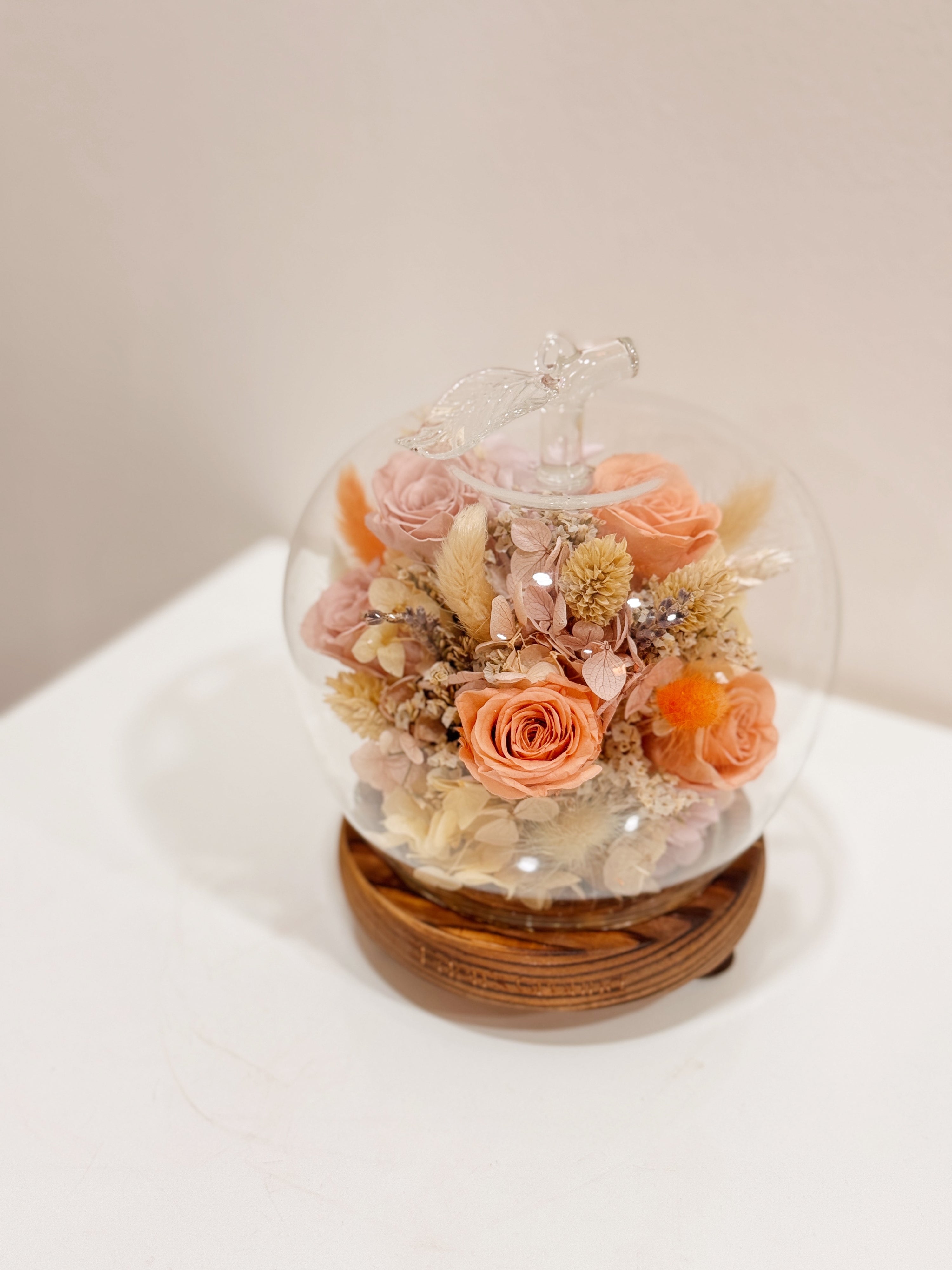 Preserved and dried flowers in soft peach tones, elegantly arranged in a lighted apple-shaped glass dome by Eden’s Ground—a timeless gift to warm the heart this Valentine’s Day. 