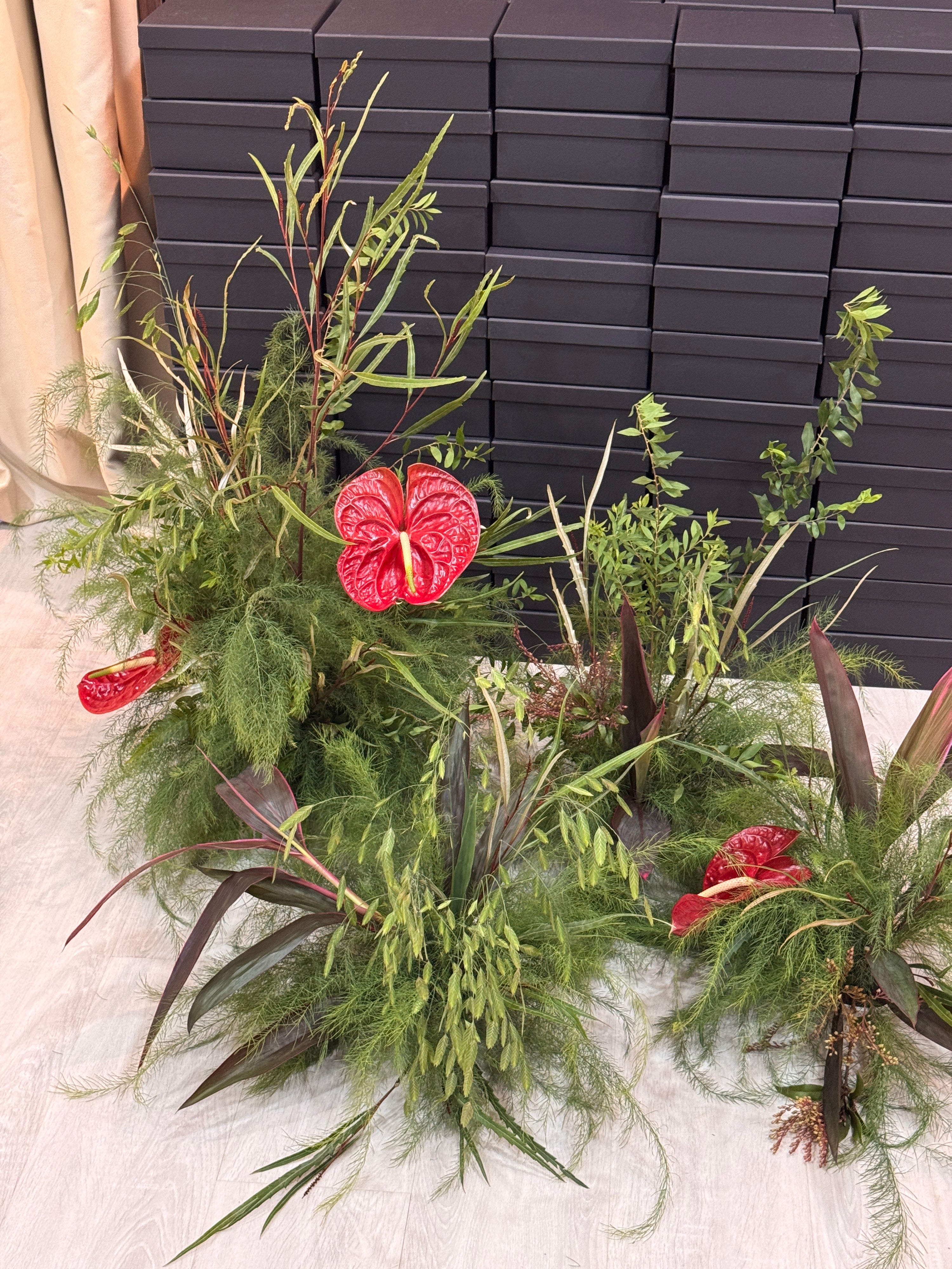 Venue styling of greenery with red flowers, crafted by Eden's Ground
