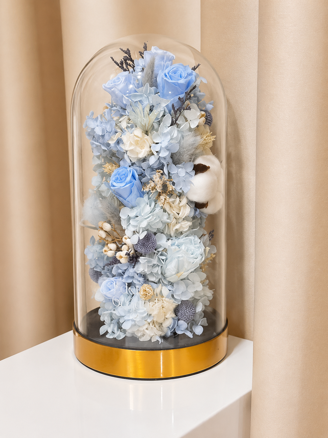 Preserved flower dome with blue blooms for gender reveal, or customisable to preferred colours, styled in a premium lighted glass dome on a gold base. Crafted by Eden's Ground, a floral design boutique.