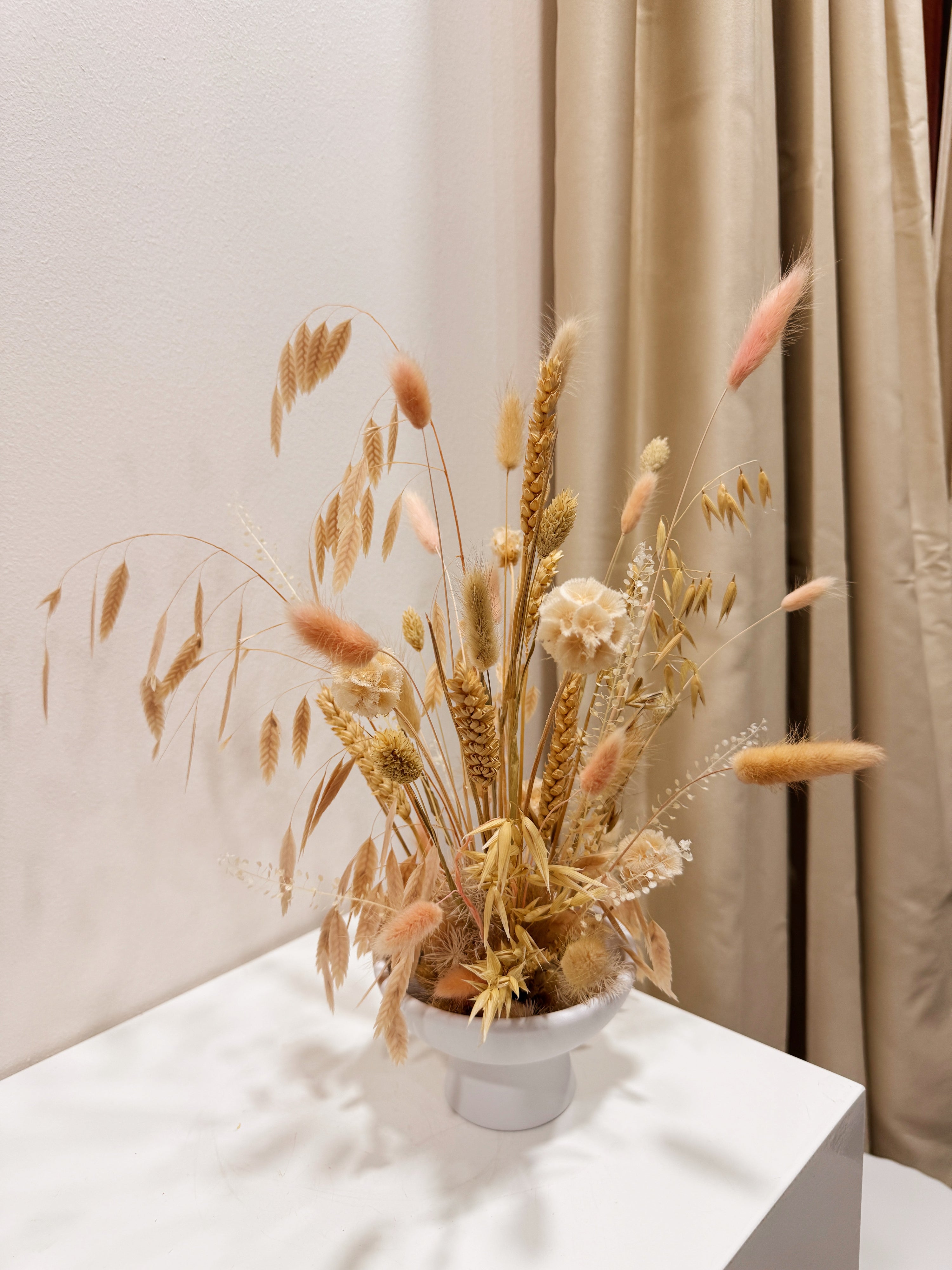 Blushing Prairie vase arrangement, an airy floral arrangement featuring preserved bunny tails, rye, wheat, and a medley of textured natural foliage—artfully styled in a low vase, thoughtfully crafted by Eden’s Ground.