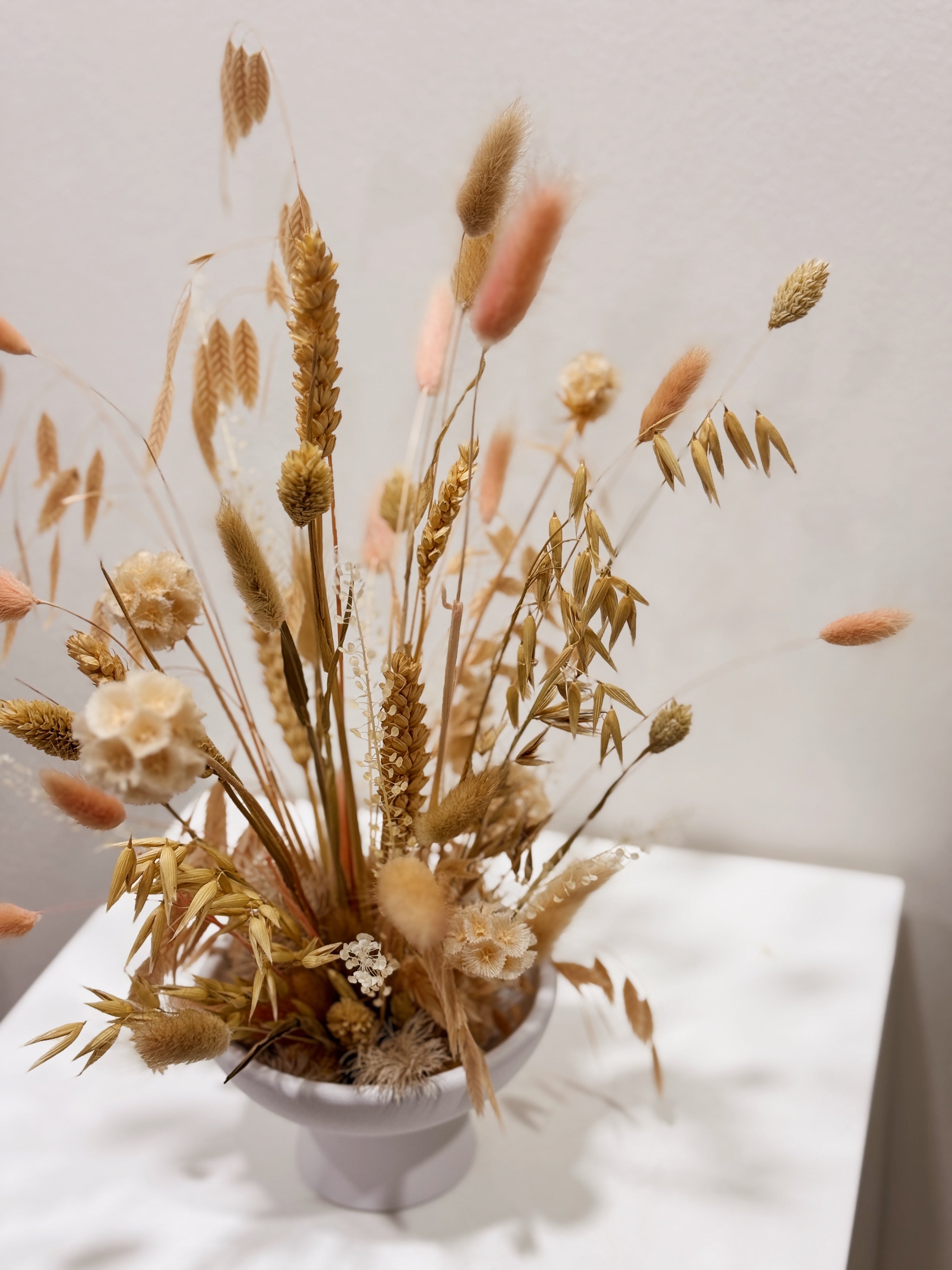 Blushing Prairie vase arrangement, an airy floral arrangement featuring preserved bunny tails, rye, wheat, and a medley of textured natural foliage—artfully styled in a low vase, thoughtfully crafted by Eden’s Ground.