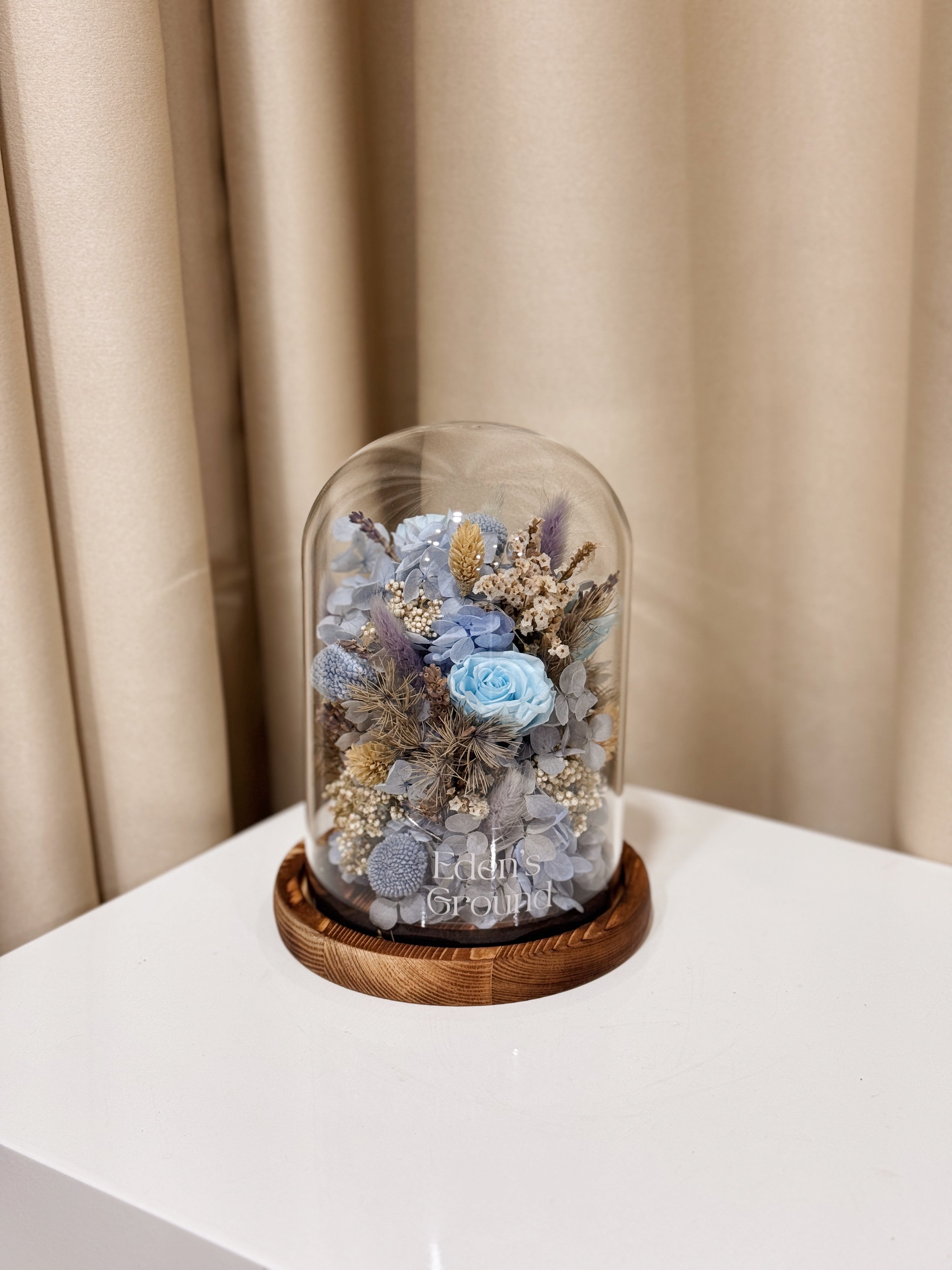Cloud Garden Preserved Flower Dome is made with a delicate blend of preserved and dried flowers in shades of blue, beautifully arranged in a glass dome by Eden’s Ground—an unforgettable gift or home decor made to last. 