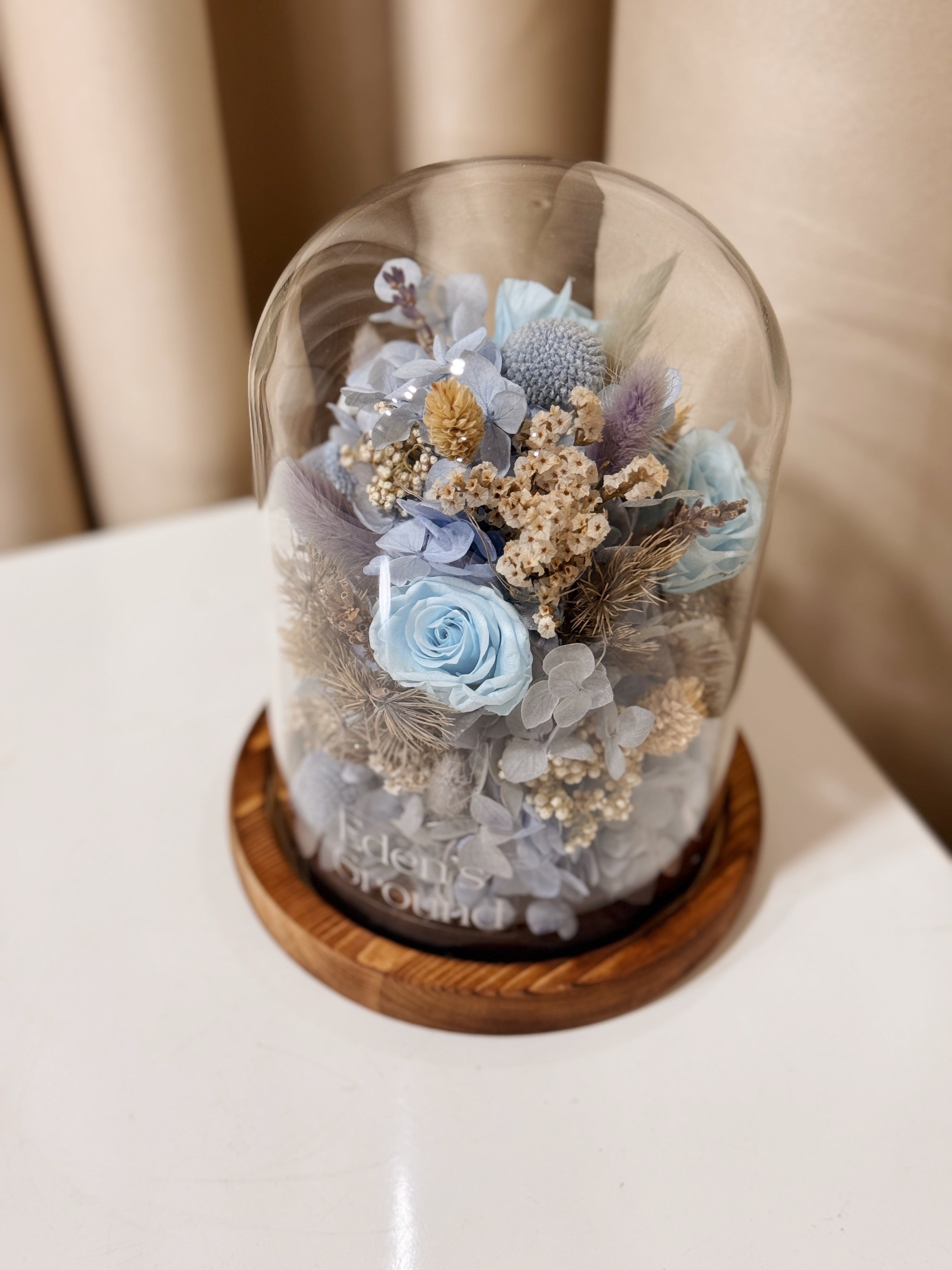 Cloud Garden Preserved Flower Dome is made with a delicate blend of preserved and dried flowers in shades of blue, beautifully arranged in a glass dome by Eden’s Ground—an unforgettable gift or home decor made to last. 
