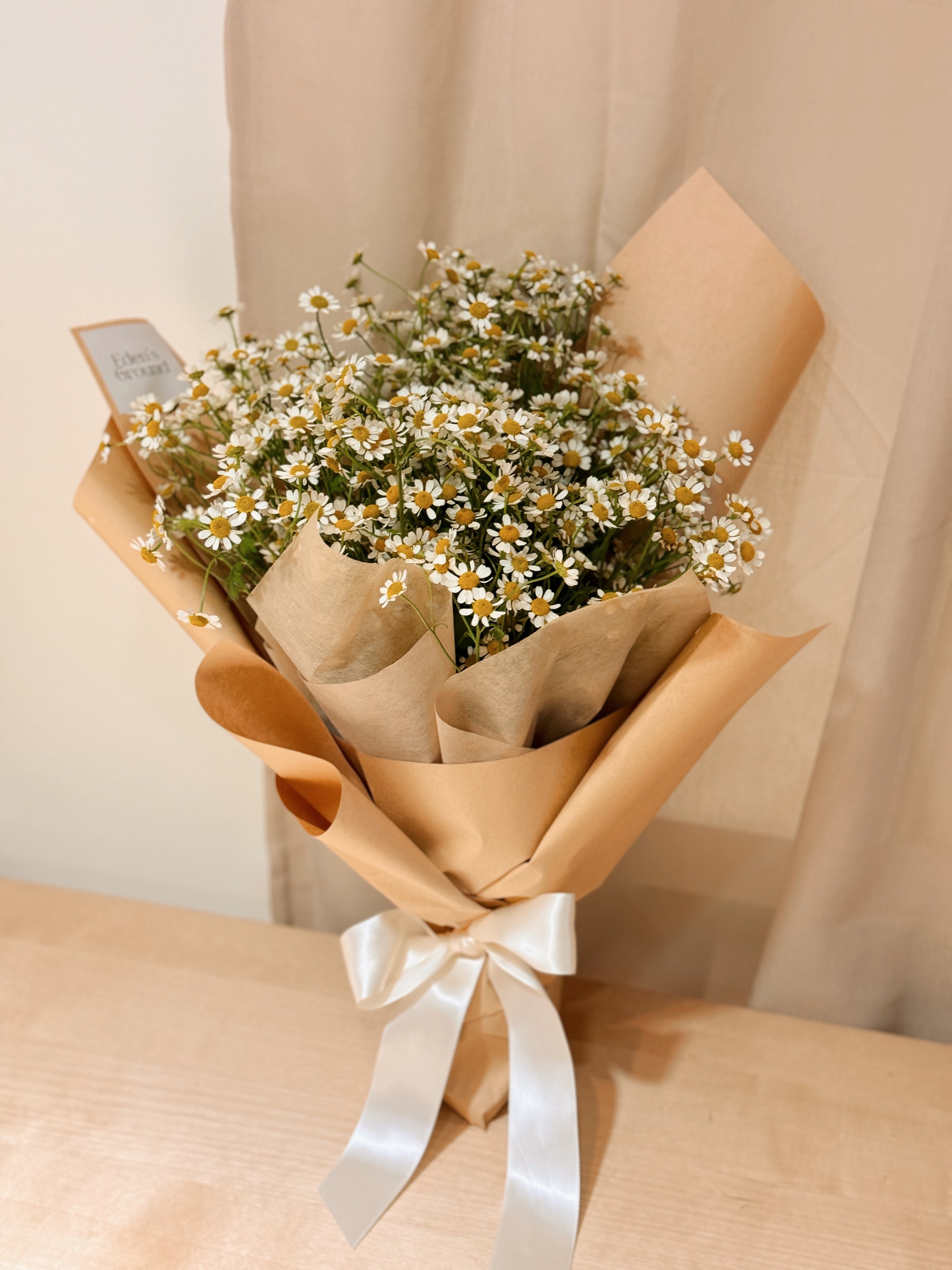 Crazies for daisies chamomile daisy bouquet wrapped in brown tissue paper and brown kraft paper crafted by Eden’s Ground.