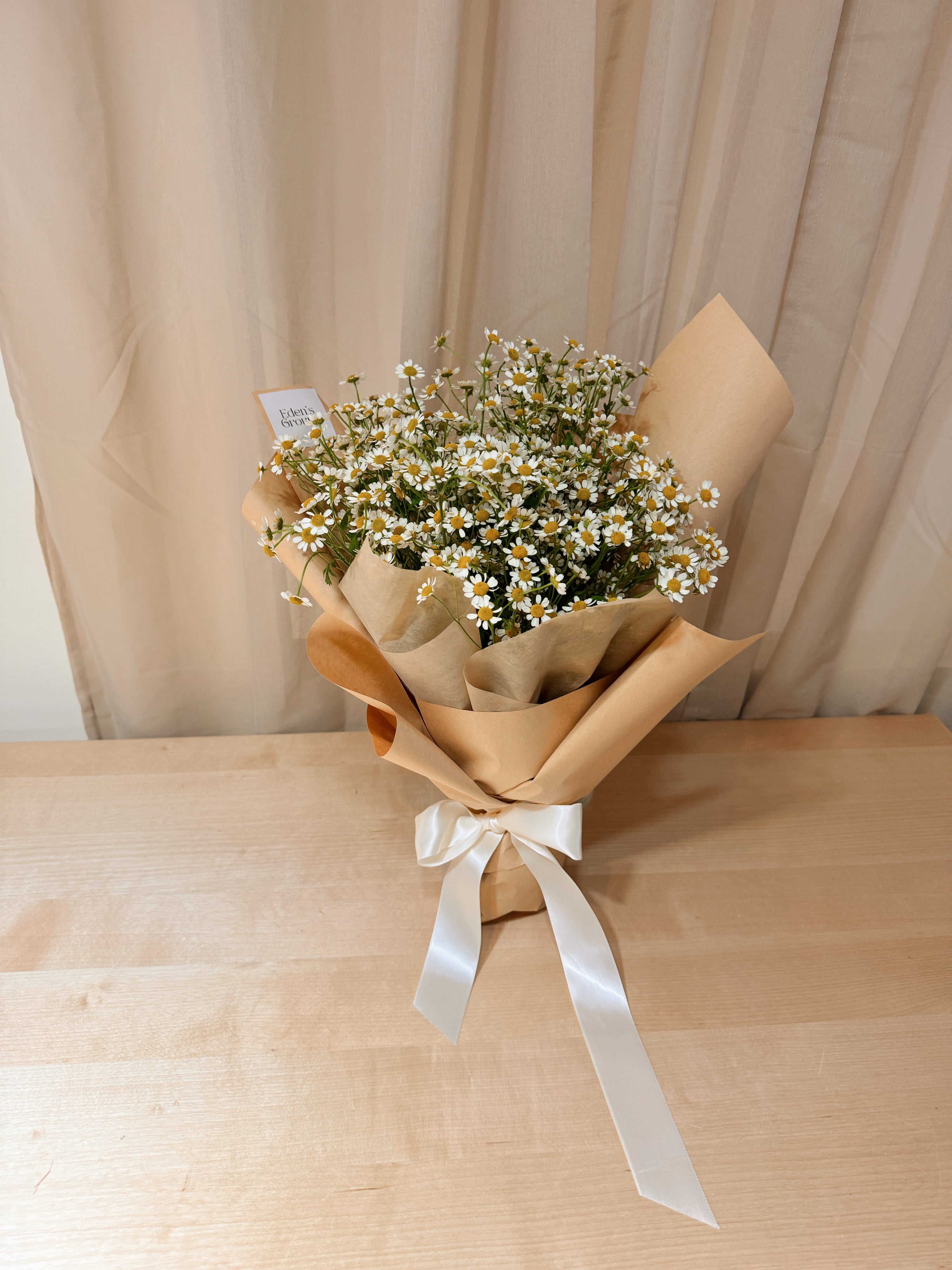 Crazies for daisies chamomile daisy bouquet wrapped in brown tissue paper and brown kraft paper crafted by Eden’s Ground.