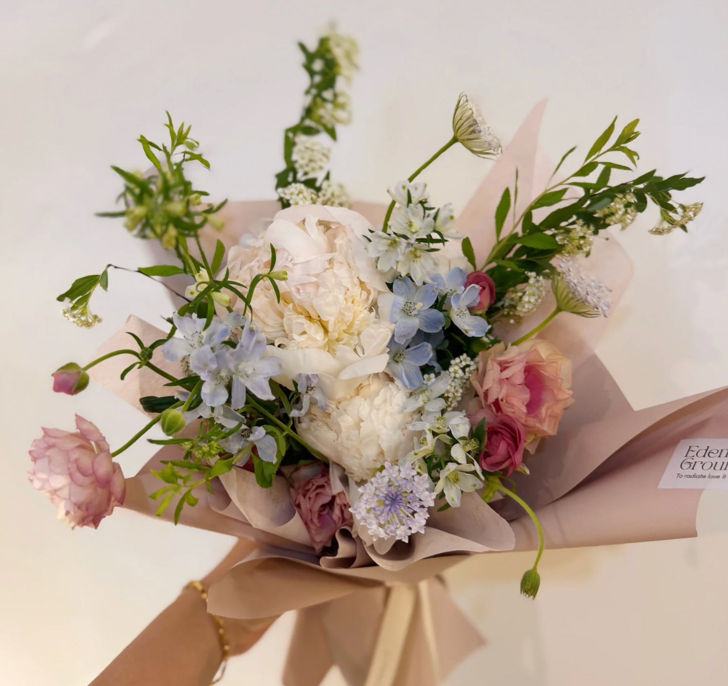 Bouquet of flowers with white, pink, and green colors on a light background.
