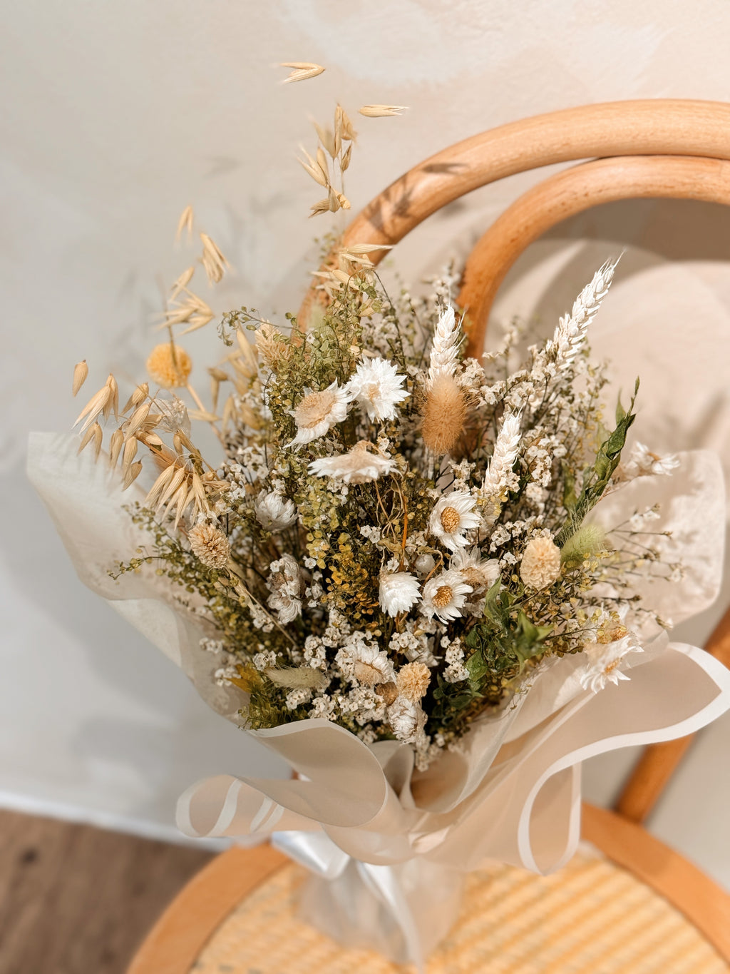 Forest nymph dried flower bouquet made of earth-toned, nature-inspired wildflowers, featuring delicate chamomile daisy and textural foliage, wrapped in glassine paper crafted by Eden’s Ground.