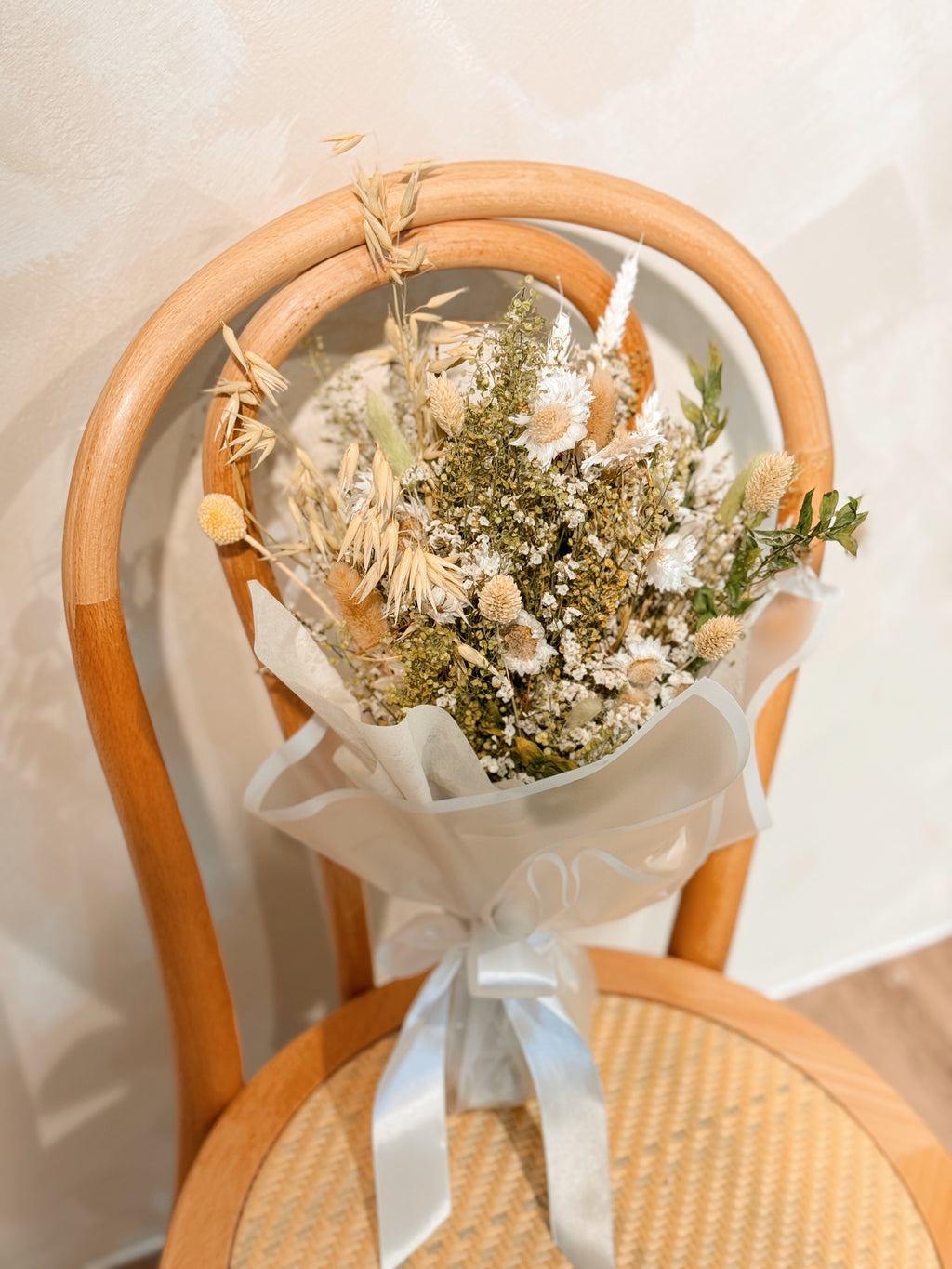 Forest nymph dried flower bouquet made of earth-toned, nature-inspired wildflowers, featuring delicate chamomile daisy and textural foliage, wrapped in glassine paper crafted by Eden’s Ground.