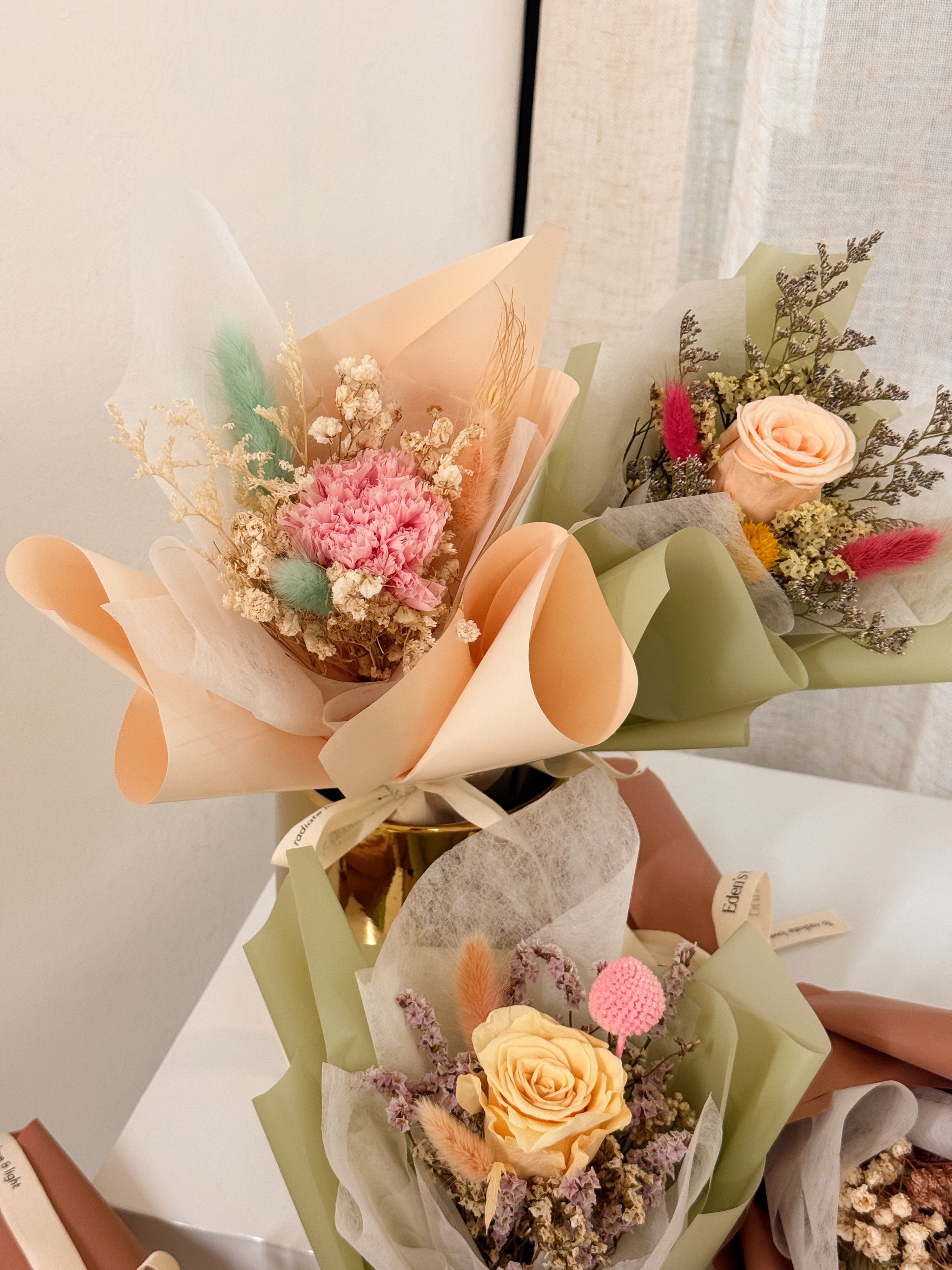 From the bottom of my heart bouquet, a simple single flower bouquet, featuring either roses or carnation, with hydrangea and various filler flowers, wrapped with white tissue and brown kraft or glassine paper, crafted by Eden's Ground.