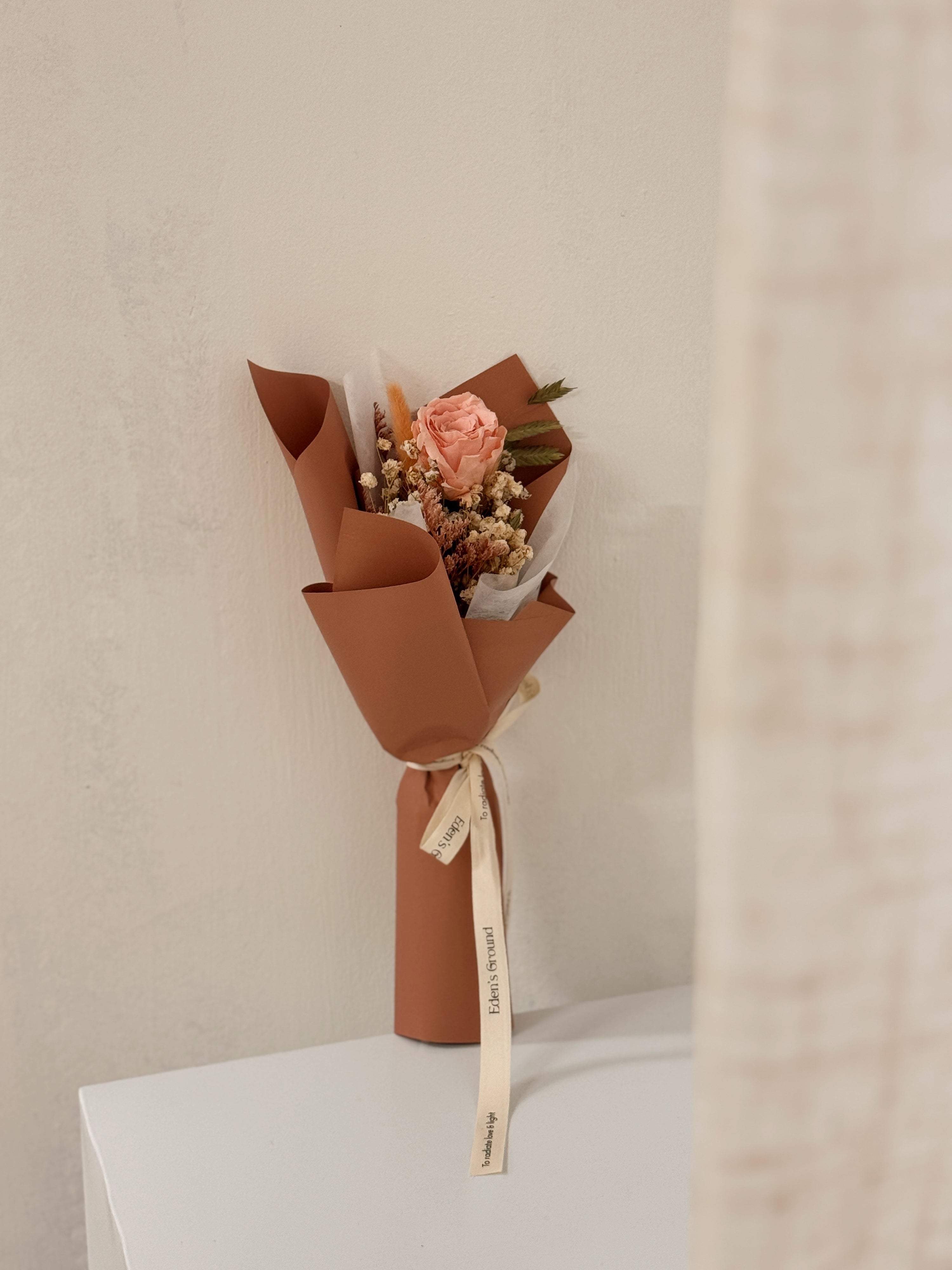 From the bottom of my heart bouquet, a simple single flower bouquet, featuring either roses or carnation, with hydrangea and various filler flowers, wrapped with white tissue and brown kraft or glassine paper, crafted by Eden's Ground.