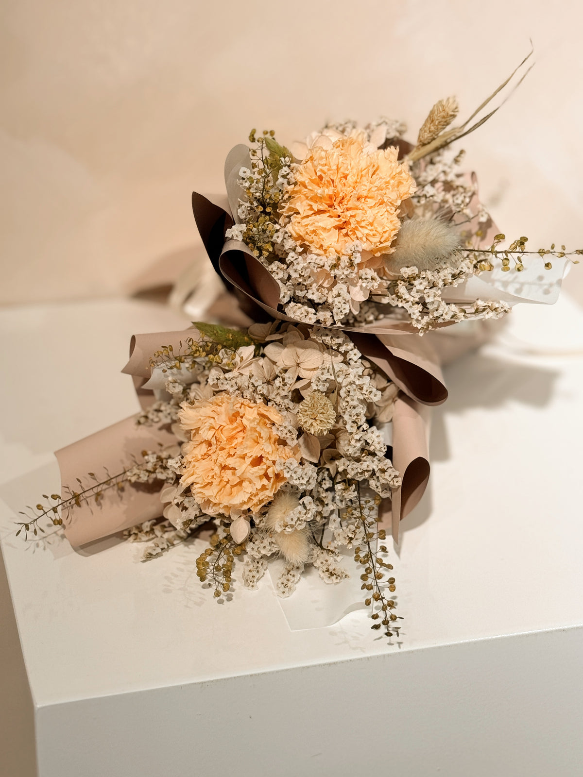 From the heart bouquet, a simple single flower bouquet, featuring either roses or carnation, with hydrangea and various filler flowers, wrapped with white tissue and brown kraft or glassine paper, crafted by Eden's Ground.
