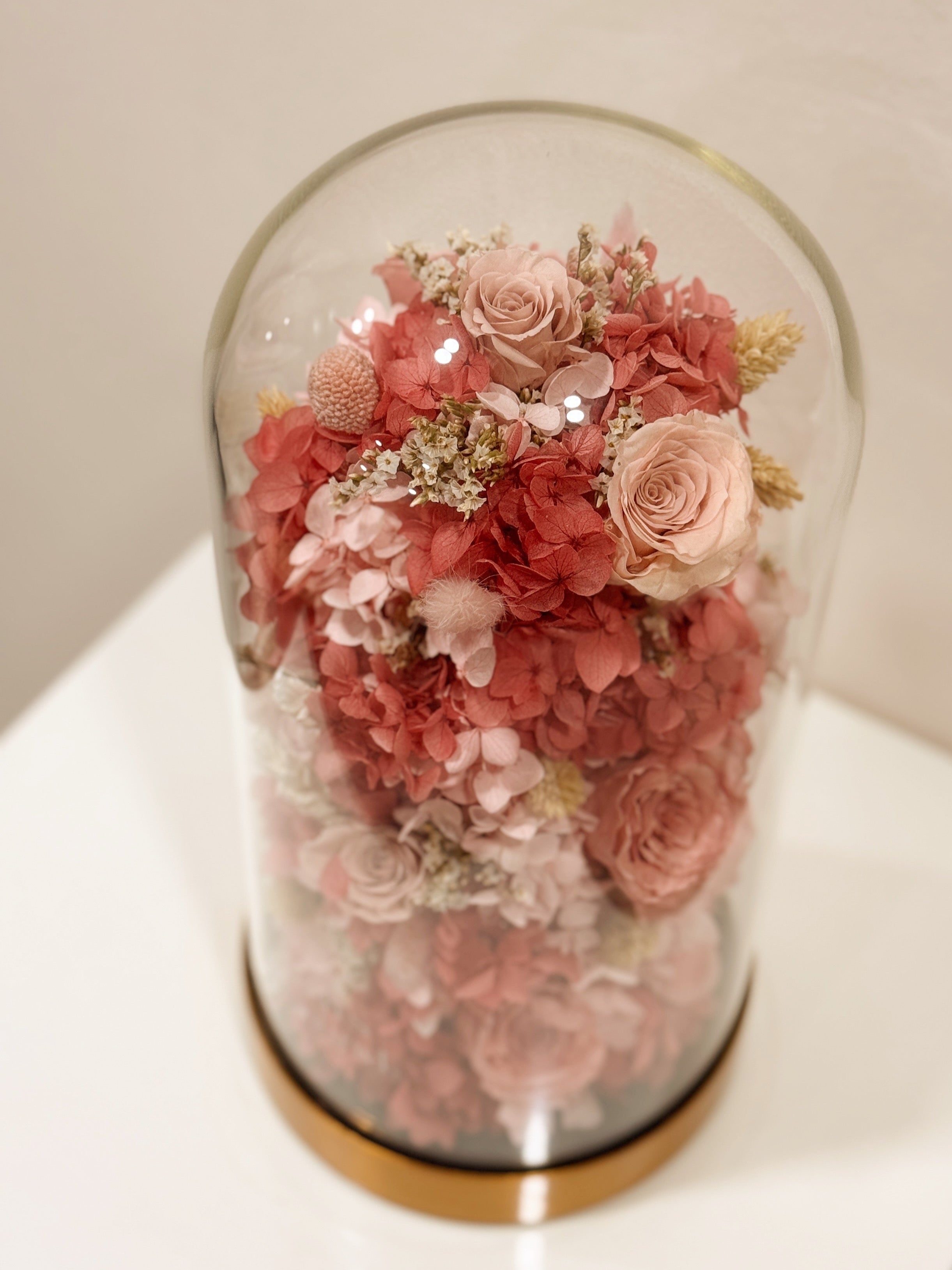 Preserved flower dome with pink or blue blooms for gender reveal, or customisable to preferred colours, styled in a premium lighted glass dome on a gold base. Crafted by Eden's Ground, a floral design boutique.