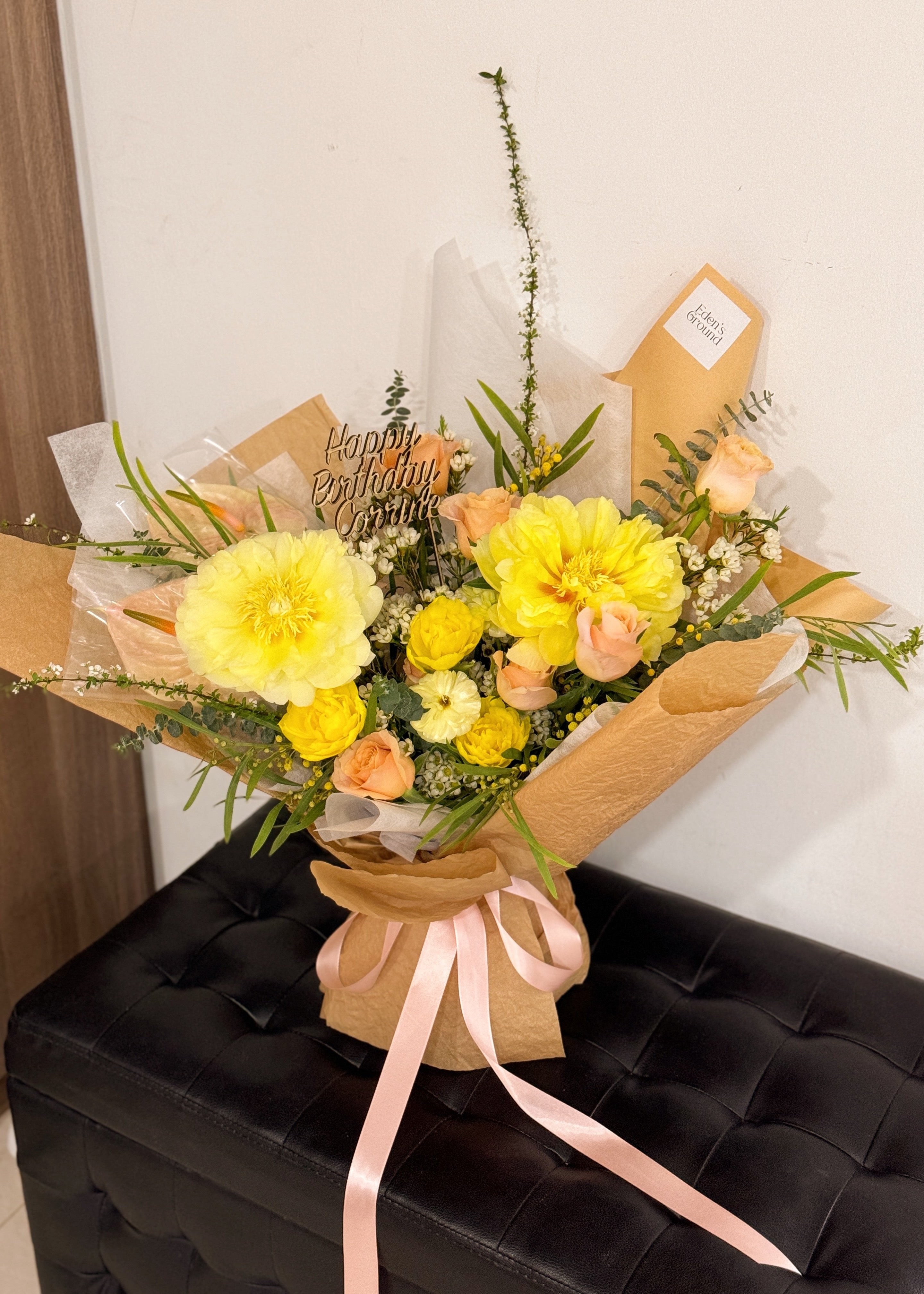 uxurious premium yellow peony bouquet featuring peonies, roses, along with filler flowers and foliage like eucalyptus, wrapped in tissue paper and brown kraft paper, crafted by Eden's Ground. 