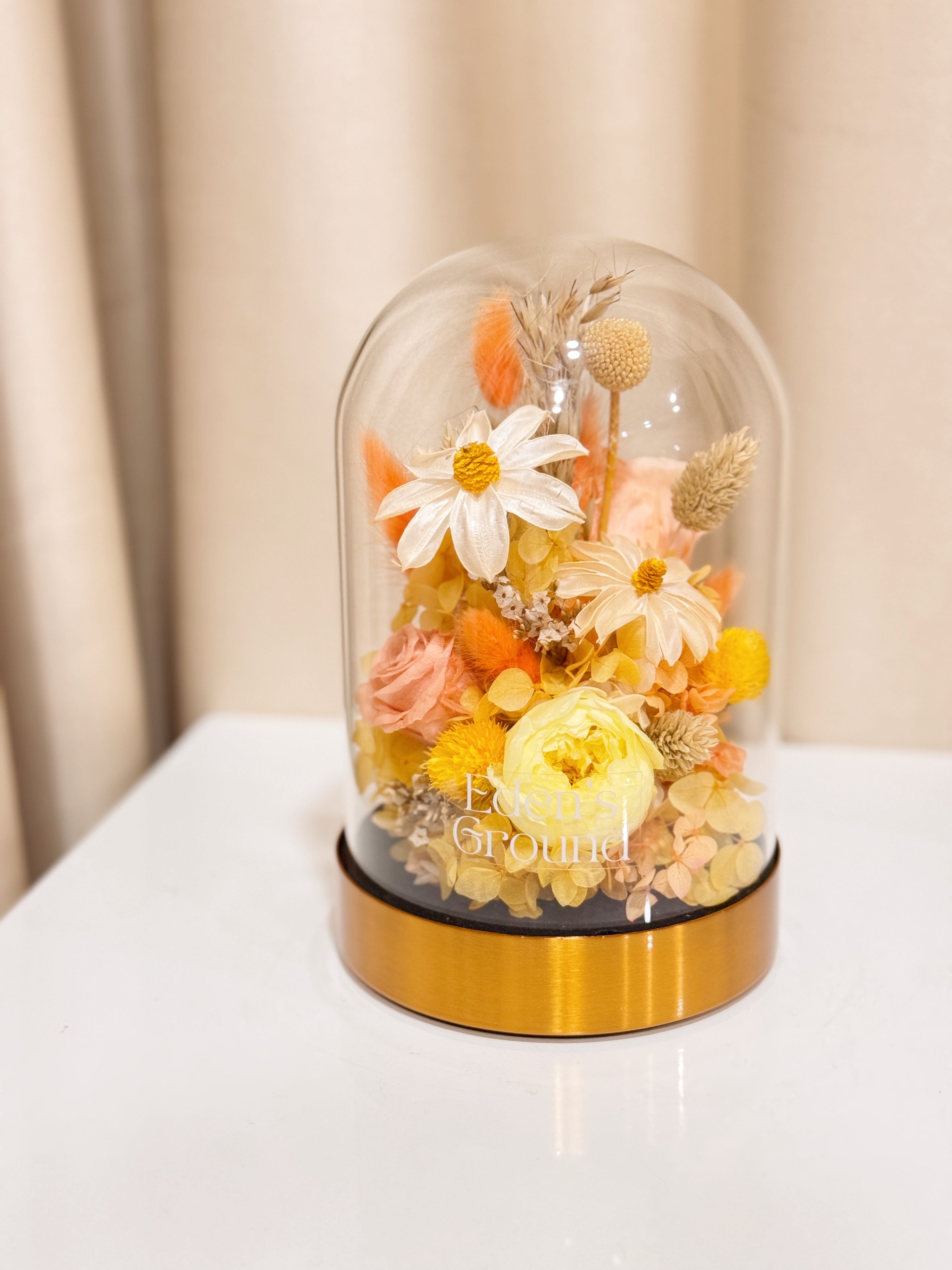 Everlasting Lemon Meringue Flower Dome is made with a delicate blend of preserved cheerful yellow roses, and flowers in a variety of soft pastel colours, beautifully arranged in a glass dome by Eden’s Ground—an unforgettable gift or home decor made to last. 