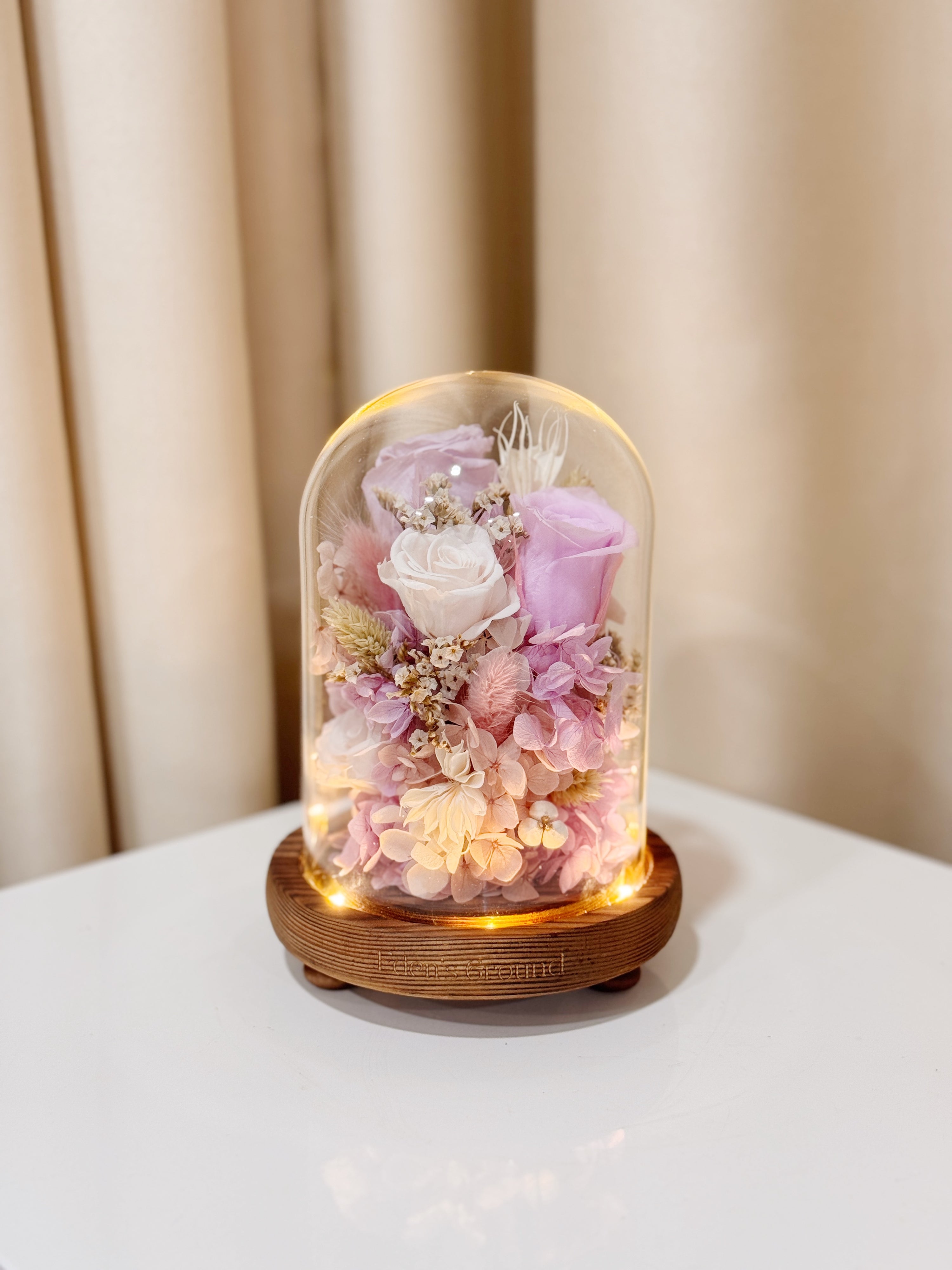 Everlasting Lilac Enchantment Flower Dome is made with a delicate blend of preserved lavender and purple roses, and flowers in a variety of soft pastel colours, beautifully arranged in a glass dome by Eden’s Ground—an unforgettable gift or home decor made to last. 