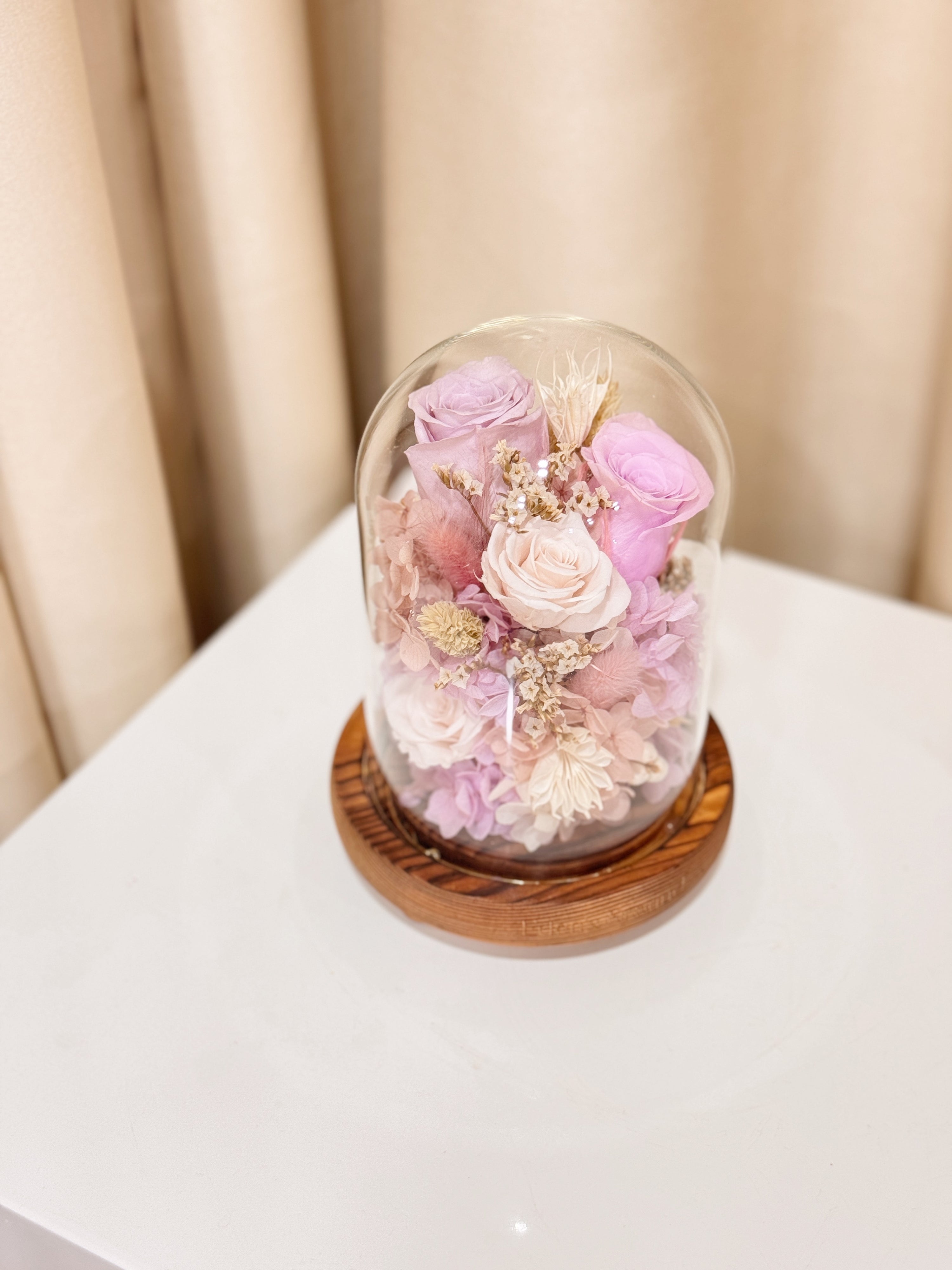 Everlasting Lilac Enchantment Flower Dome is made with a delicate blend of preserved lavender and purple roses, and flowers in a variety of soft pastel colours, beautifully arranged in a glass dome by Eden’s Ground—an unforgettable gift or home decor made to last. 