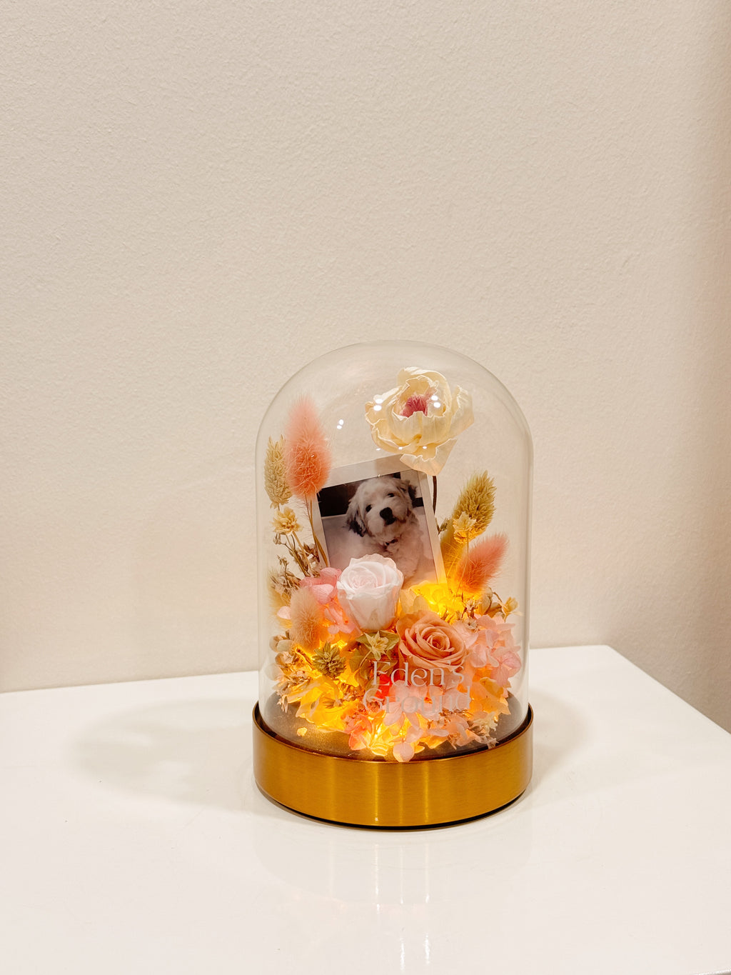 Preserved flower dome with your own photo as a memory capsule, styled in a lighted glass dome on a gold base. Crafted by Eden's Ground, a floral design boutique.