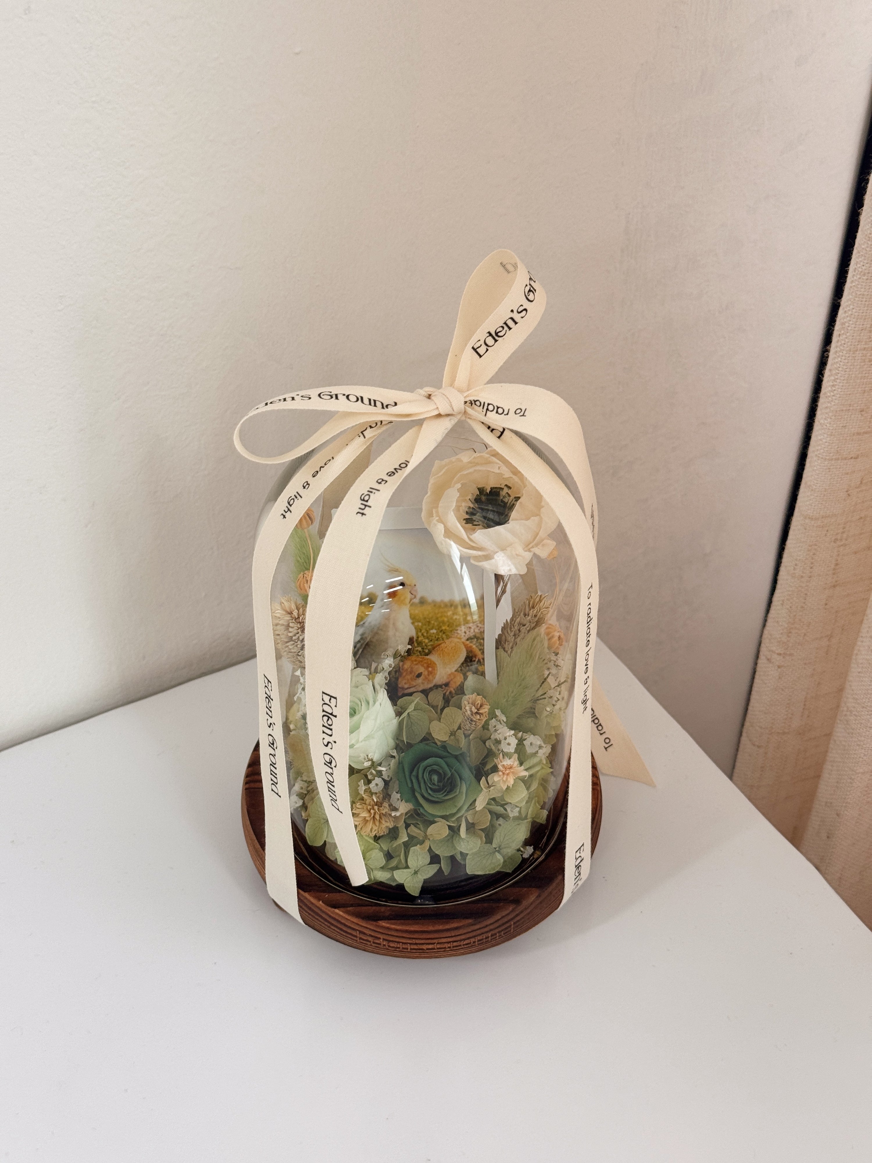 Preserved flower dome with your own photo as a memory capsule, styled in a lighted glass dome on a gold base. Crafted by Eden's Ground, a floral design boutique.