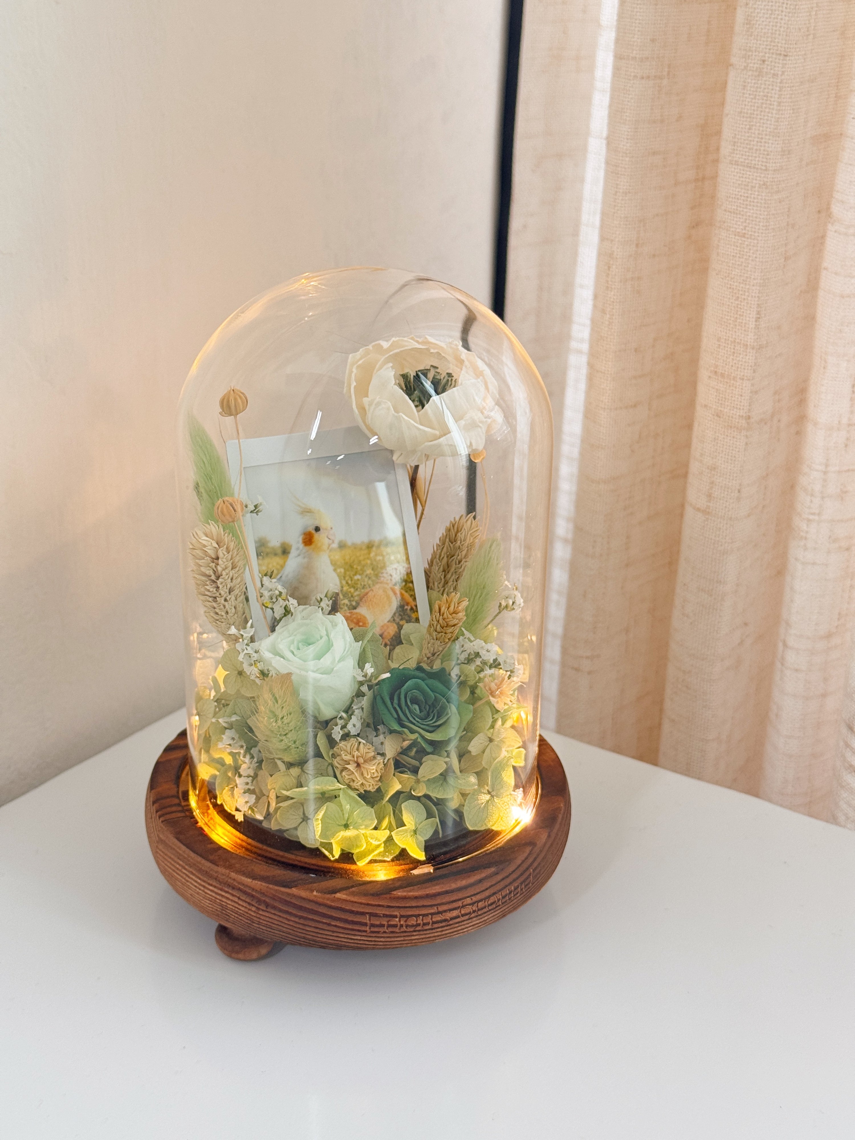Preserved flower dome with your own photo as a memory capsule, styled in a lighted glass dome on a gold base. Crafted by Eden's Ground, a floral design boutique.