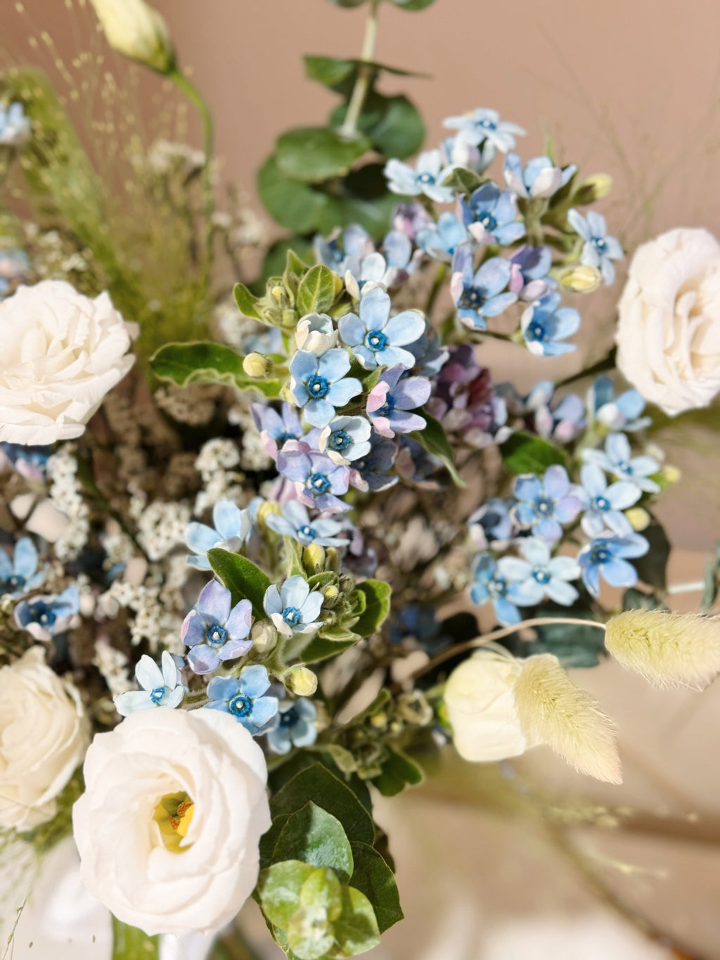 My Daystar blue tweedia bouquet featuring white eustoma, panicum and eucalyptus foliage, wrapped in white tissue paper and white glassine paper crafted by Eden’s Ground.