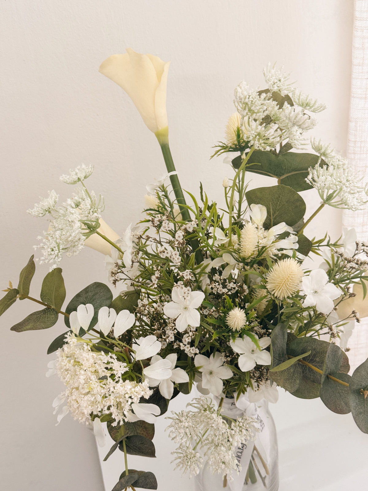 Pearl Veil Faux Flower vase arrangement by Eden’s Ground featuring life like fake flowers in soft white, earthy green tones — thoughtfully styled in a vase. Low-maintenance and long-lasting, it's perfect as a housewarming gift or as a timeless piece of home décor.