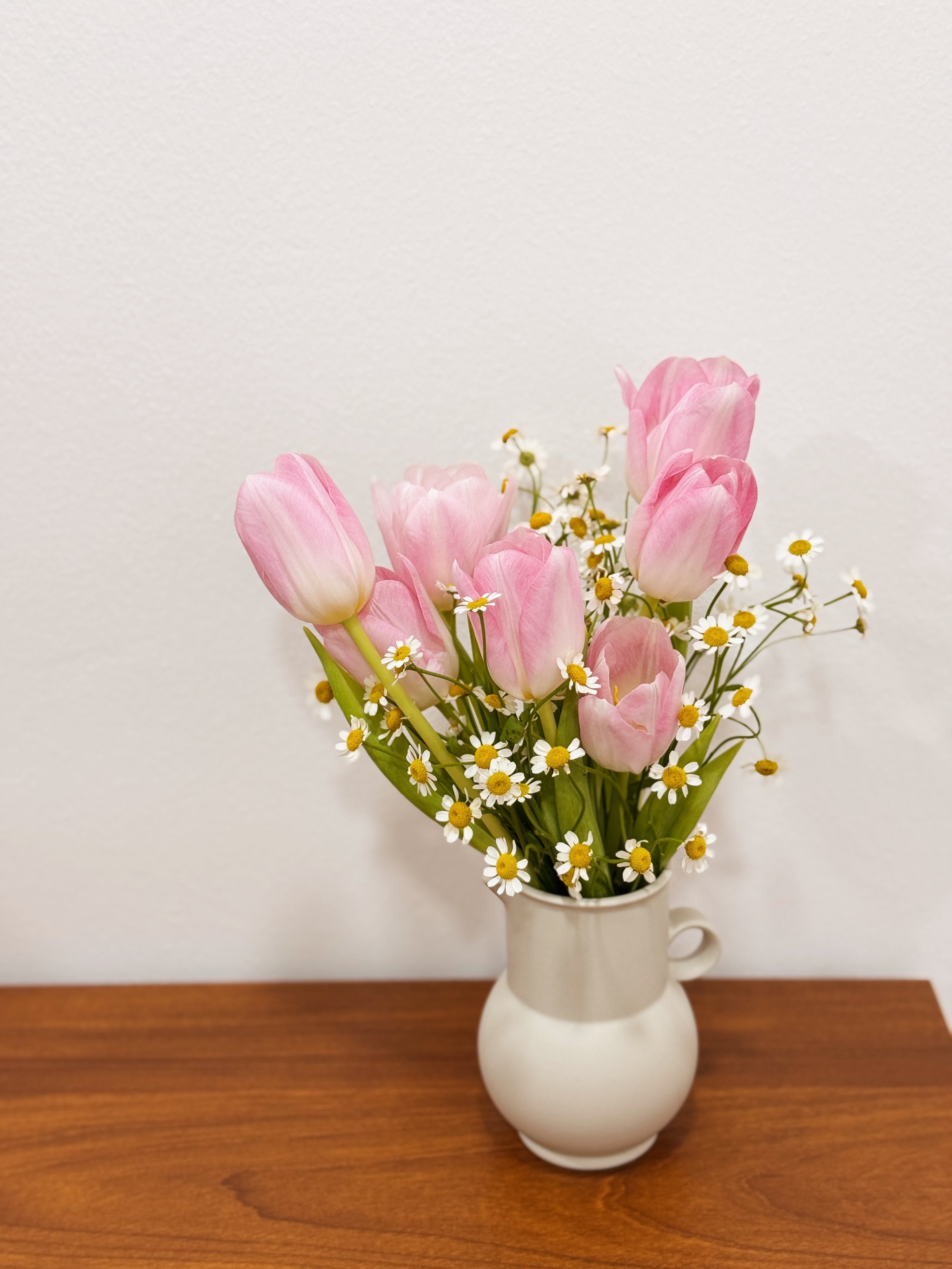Pink tulip bouquet with chamomile daisies wrapped in tissue paper and brown kraft paper crafted by Eden’s Ground.