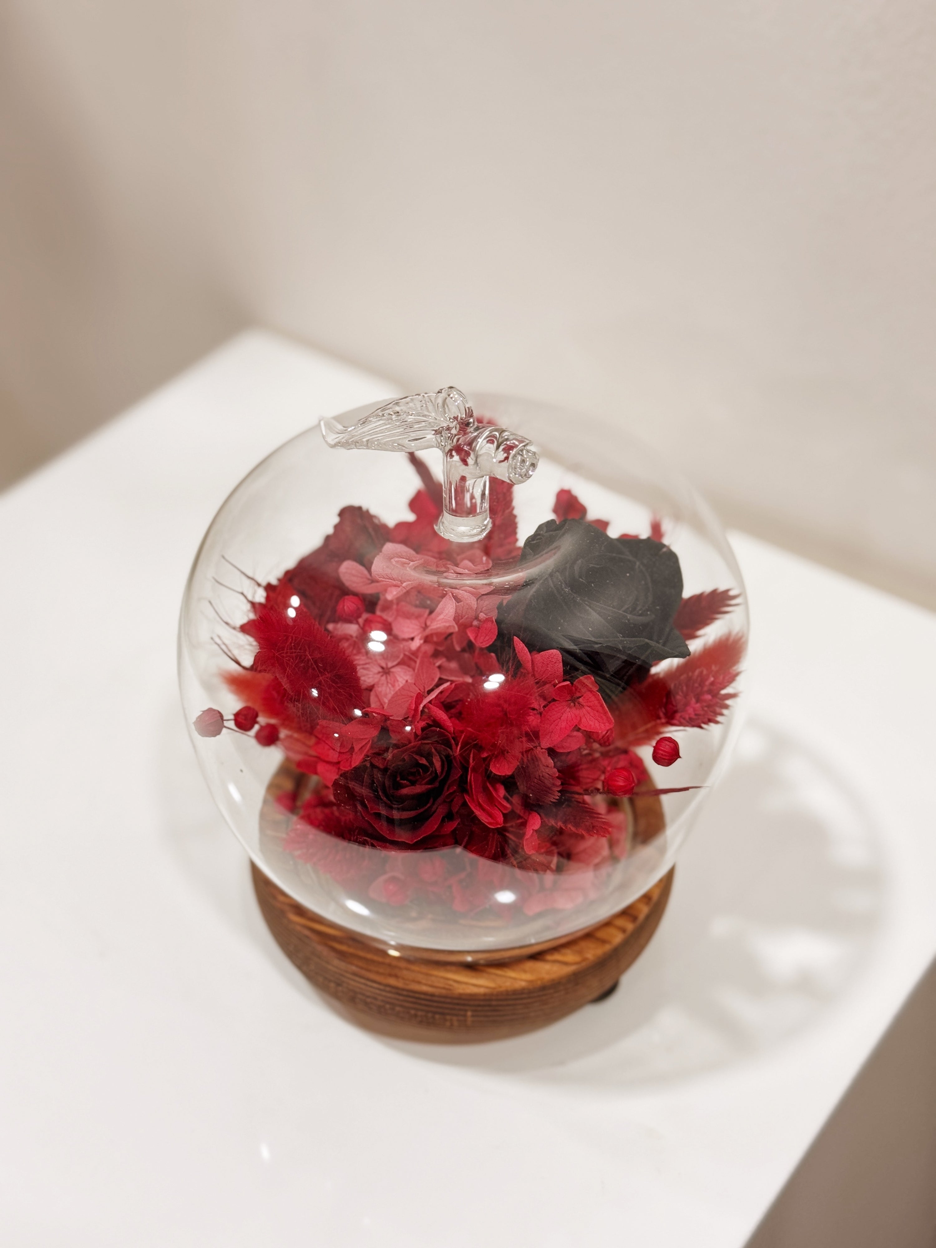 Snow white enchanted apple flower dome, inspired by fairy-tale, made with delicate blend of preserved and dried flowers in deep red tones, beautifully arranged in a lighted apple-shaped glass dome by Eden’s Ground—an enchanting keepsake made to last. 