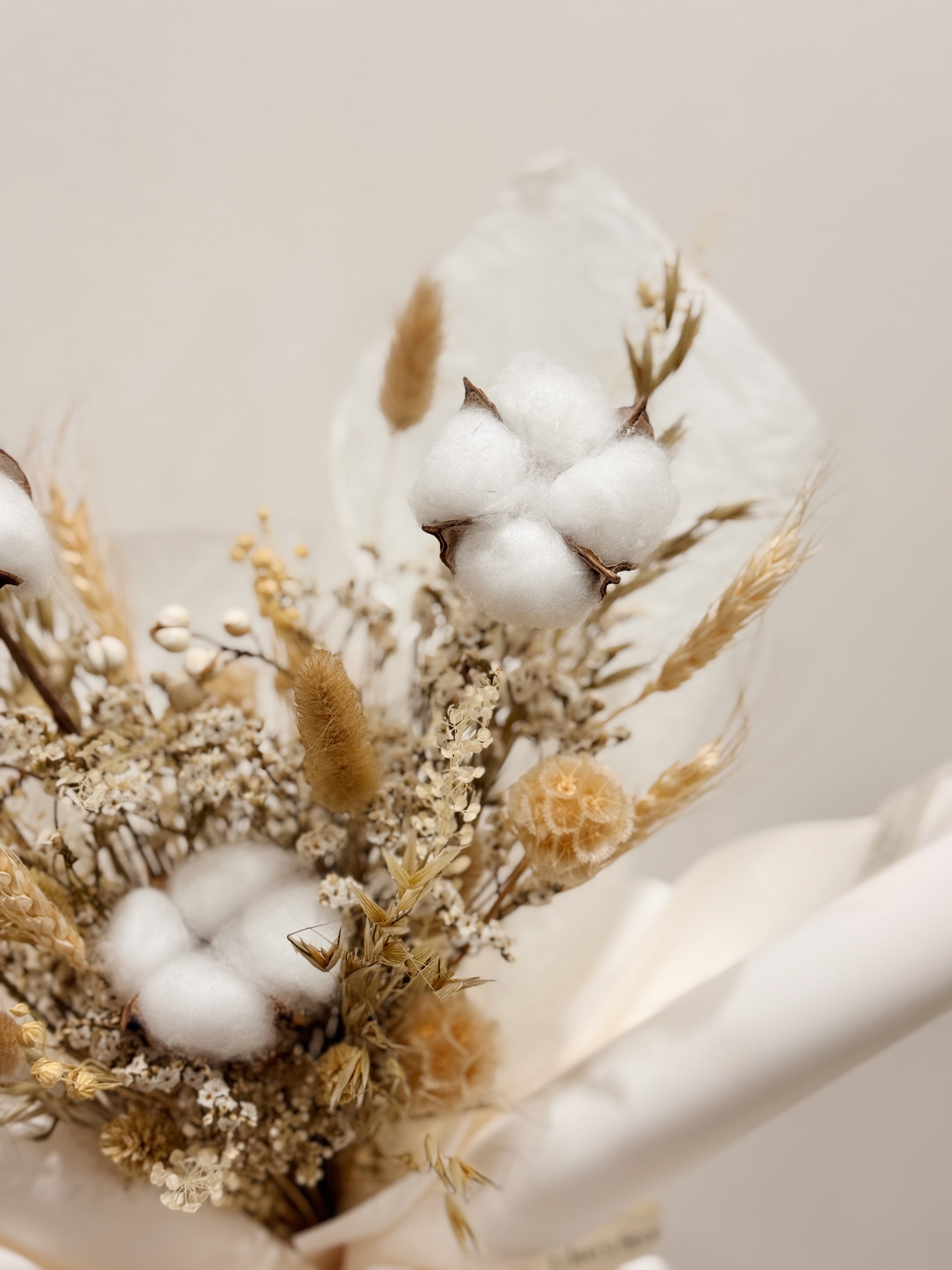 Soft Cotton bouquet made with cotton along with filler flowers and foliage, wrapped in white paper crafted by Eden’s Ground, a floral design boutique.