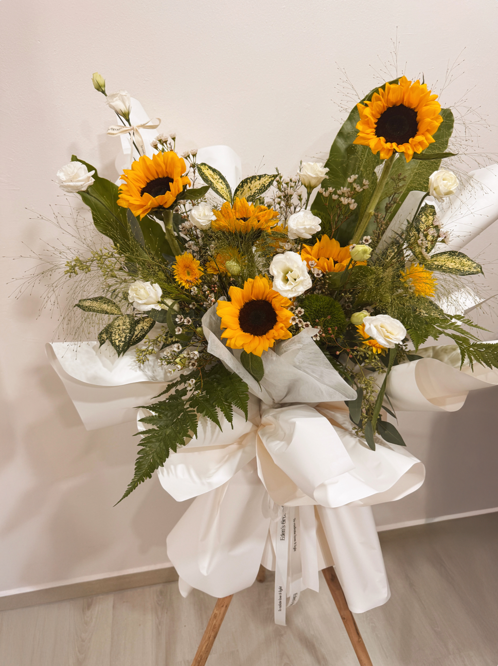Shining Success Sunflower Congratulatory Stand, featuring vibrant Sunflowers, and the fresh touch of eucalyptus, crafted by Eden's Ground, a floral design boutique based in Singapore.