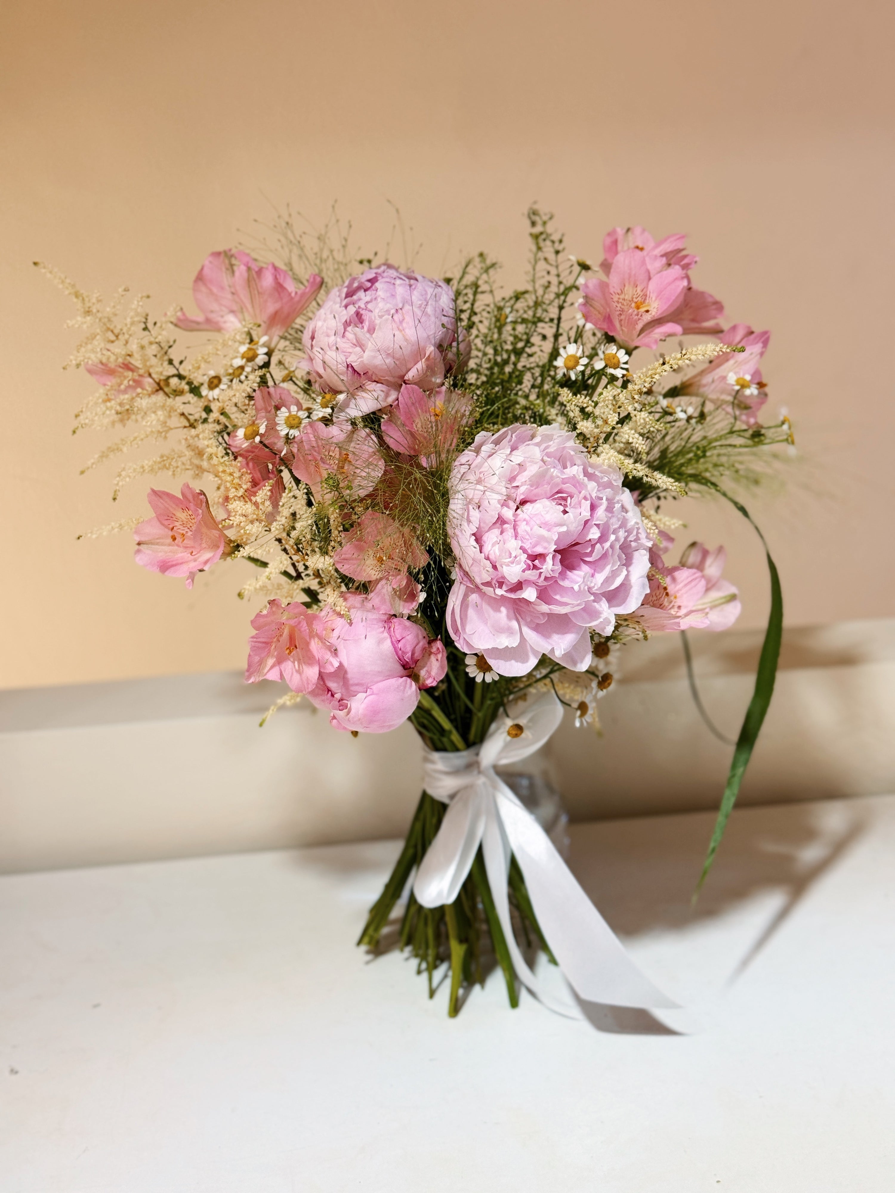 Sweeter Than Honeycomb pink peony bouquet featuring luxury peonies and a mix of textural foliage, wrapped in tissue paper and white glassine paper crafted by Eden’s Ground.