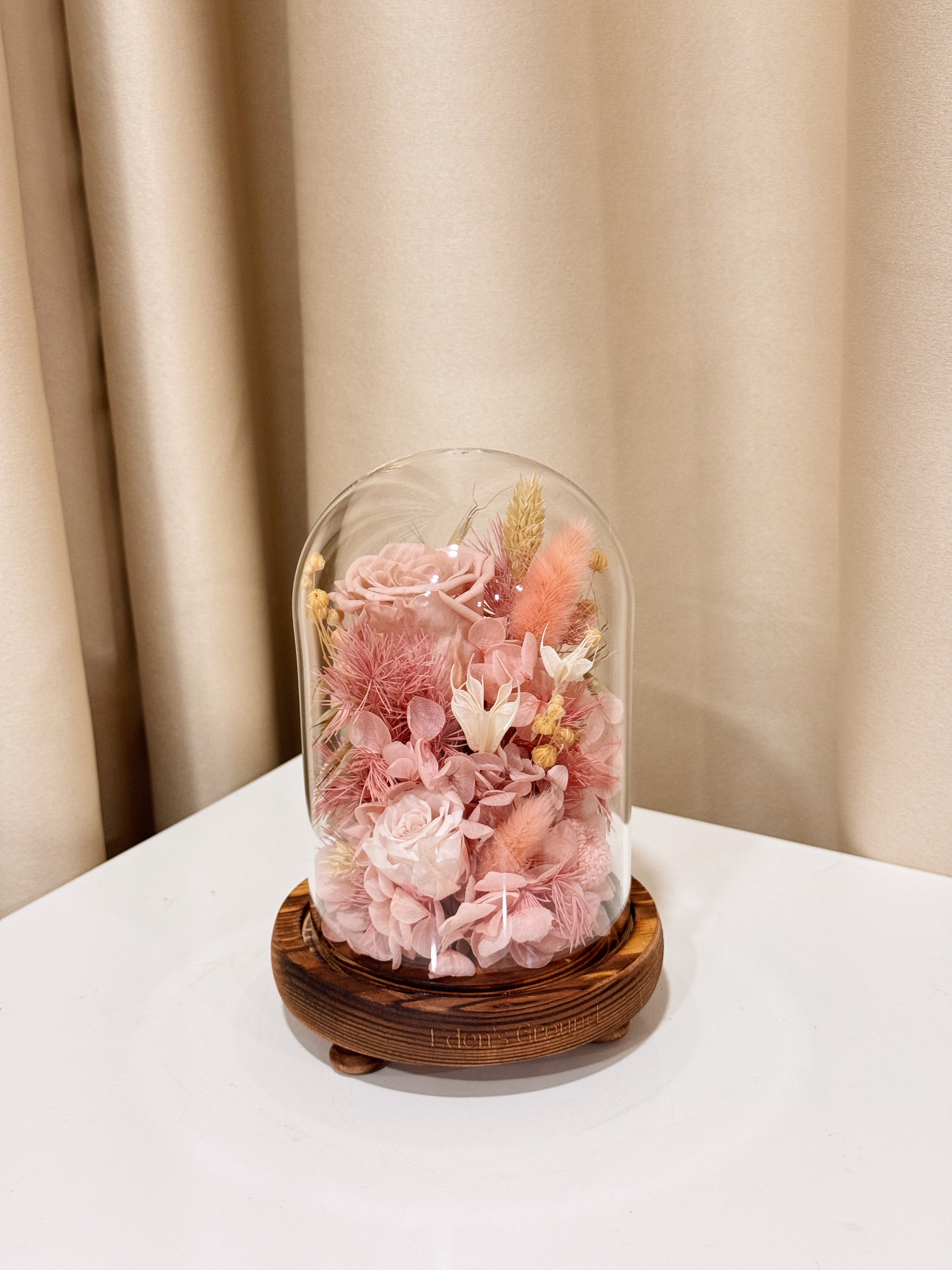 Sweetheart Gold Flower Dome is made with a delicate blend of preserved pink roses, and flowers in a variety of soft pastel colours, beautifully arranged in a glass dome by Eden’s Ground—an unforgettable gift or home decor made to last. 