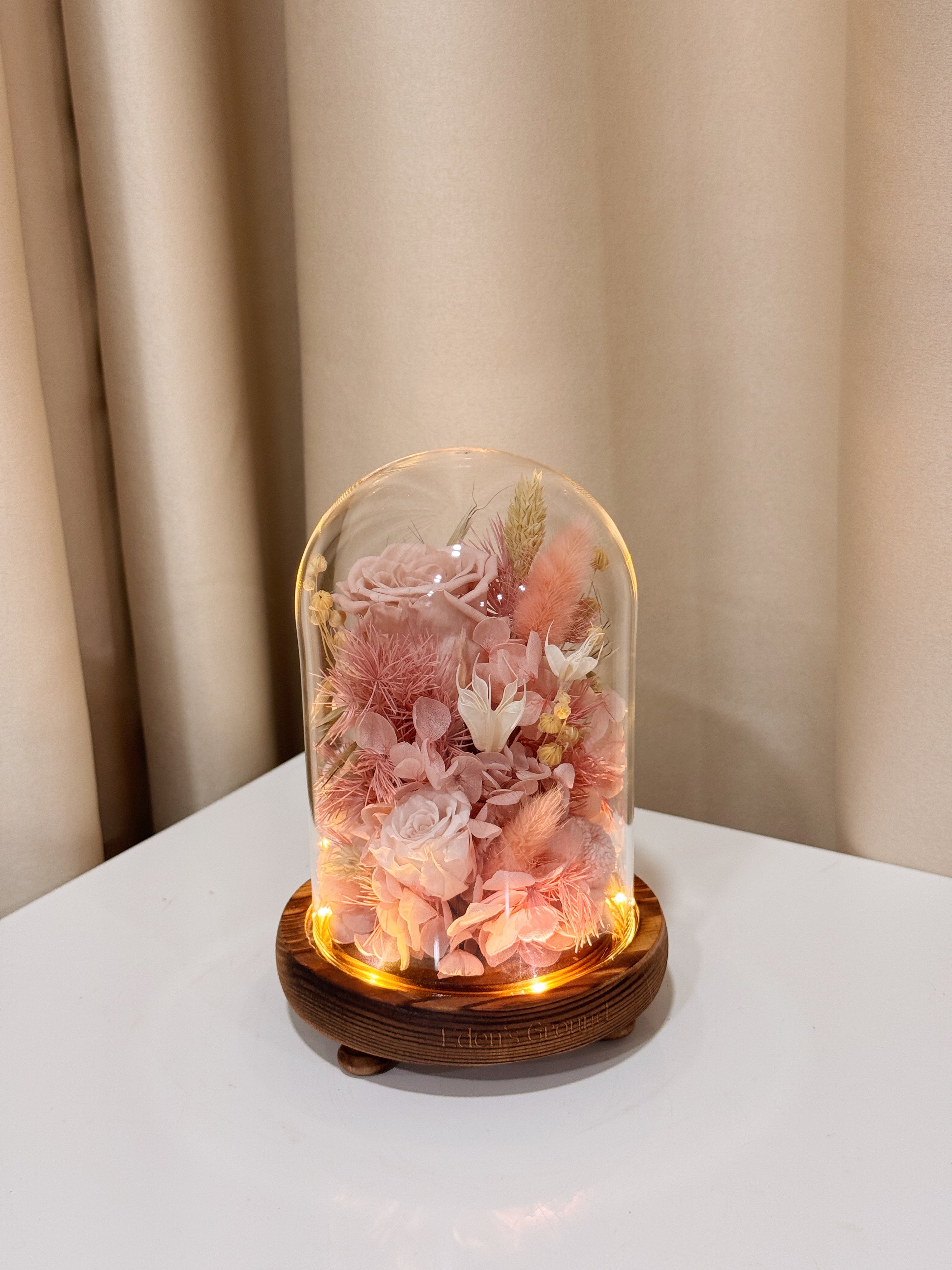 Sweetheart Gold Flower Dome is made with a delicate blend of preserved pink roses, and flowers in a variety of soft pastel colours, beautifully arranged in a glass dome by Eden’s Ground—an unforgettable gift or home decor made to last. 