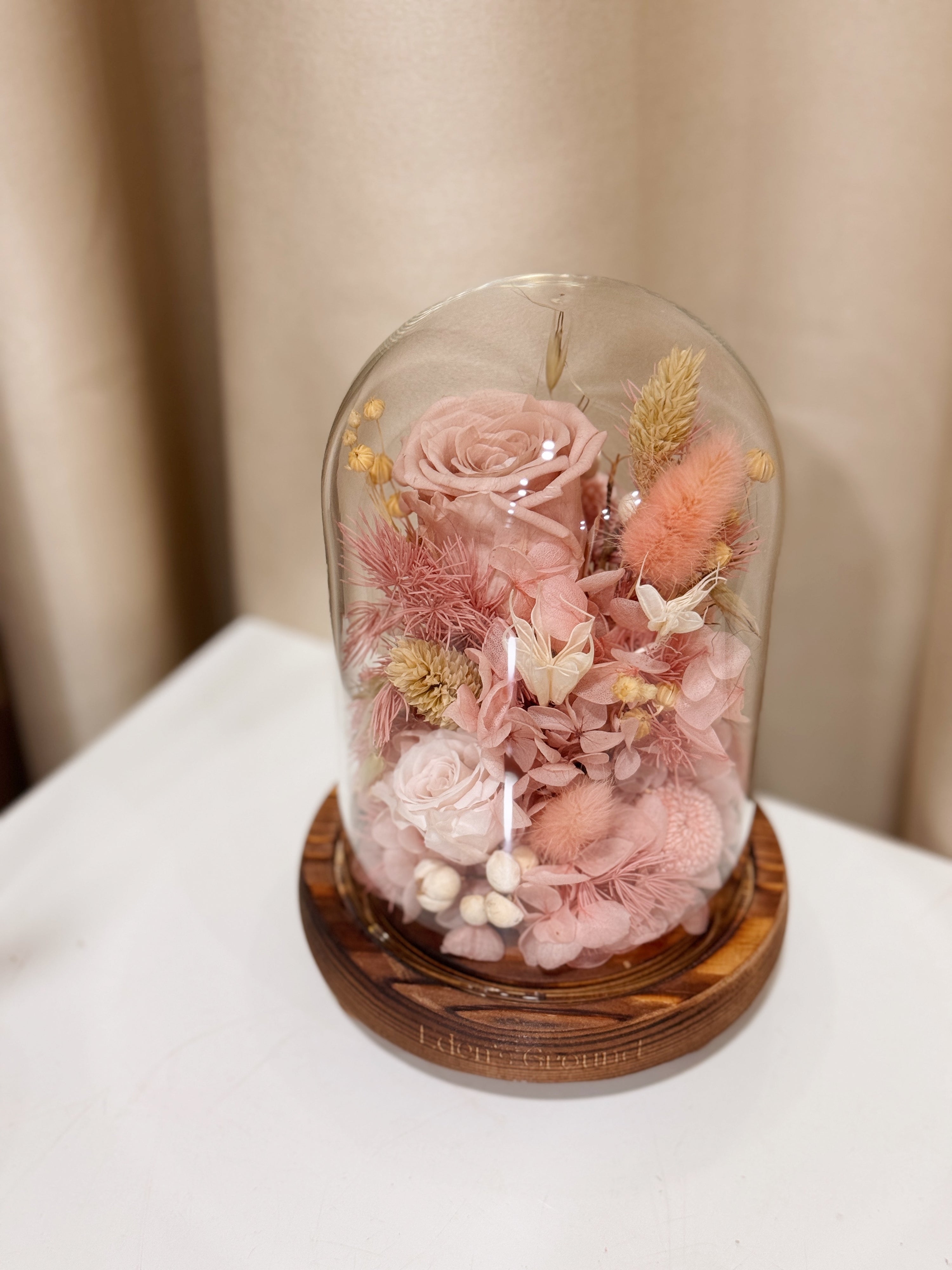 Sweetheart Gold Flower Dome is made with a delicate blend of preserved pink roses, and flowers in a variety of soft pastel colours, beautifully arranged in a glass dome by Eden’s Ground—an unforgettable gift or home decor made to last. 