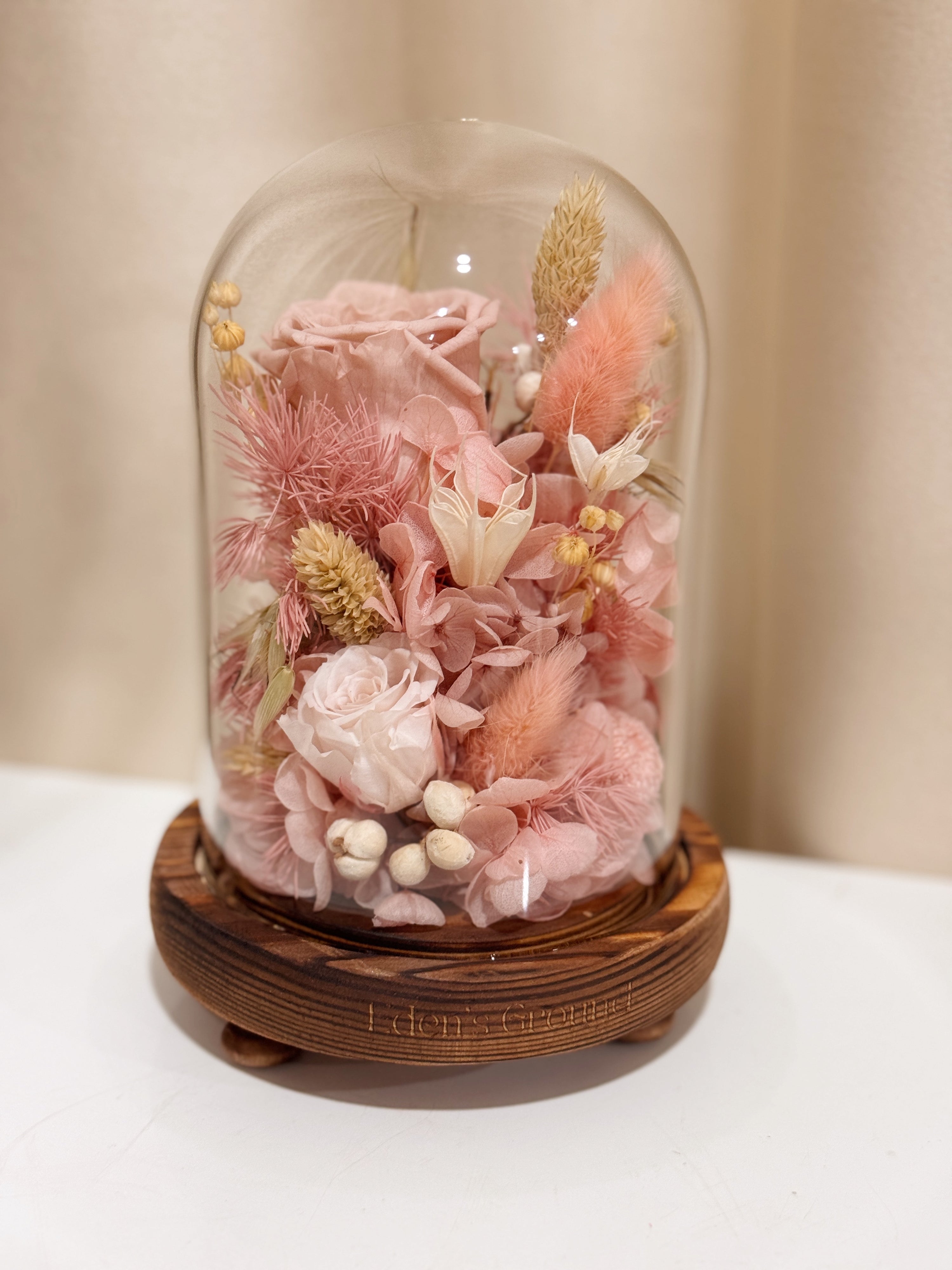 Sweetheart Gold Flower Dome is made with a delicate blend of preserved pink roses, and flowers in a variety of soft pastel colours, beautifully arranged in a glass dome by Eden’s Ground—an unforgettable gift or home decor made to last. 