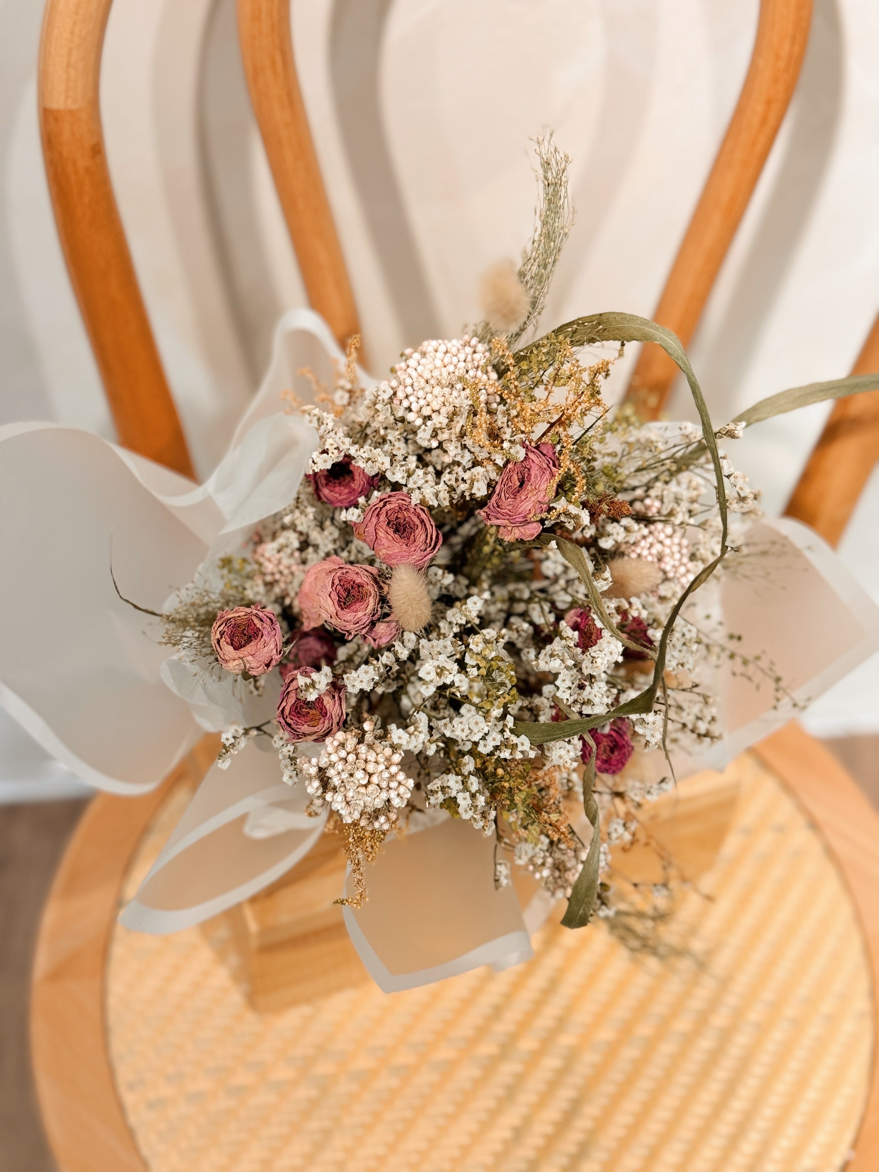 Tide of your great love, romantic dried flower bouquet featuring sweet pink roses, and textural foliage, wrapped in glassine paper crafted by Eden’s Ground.