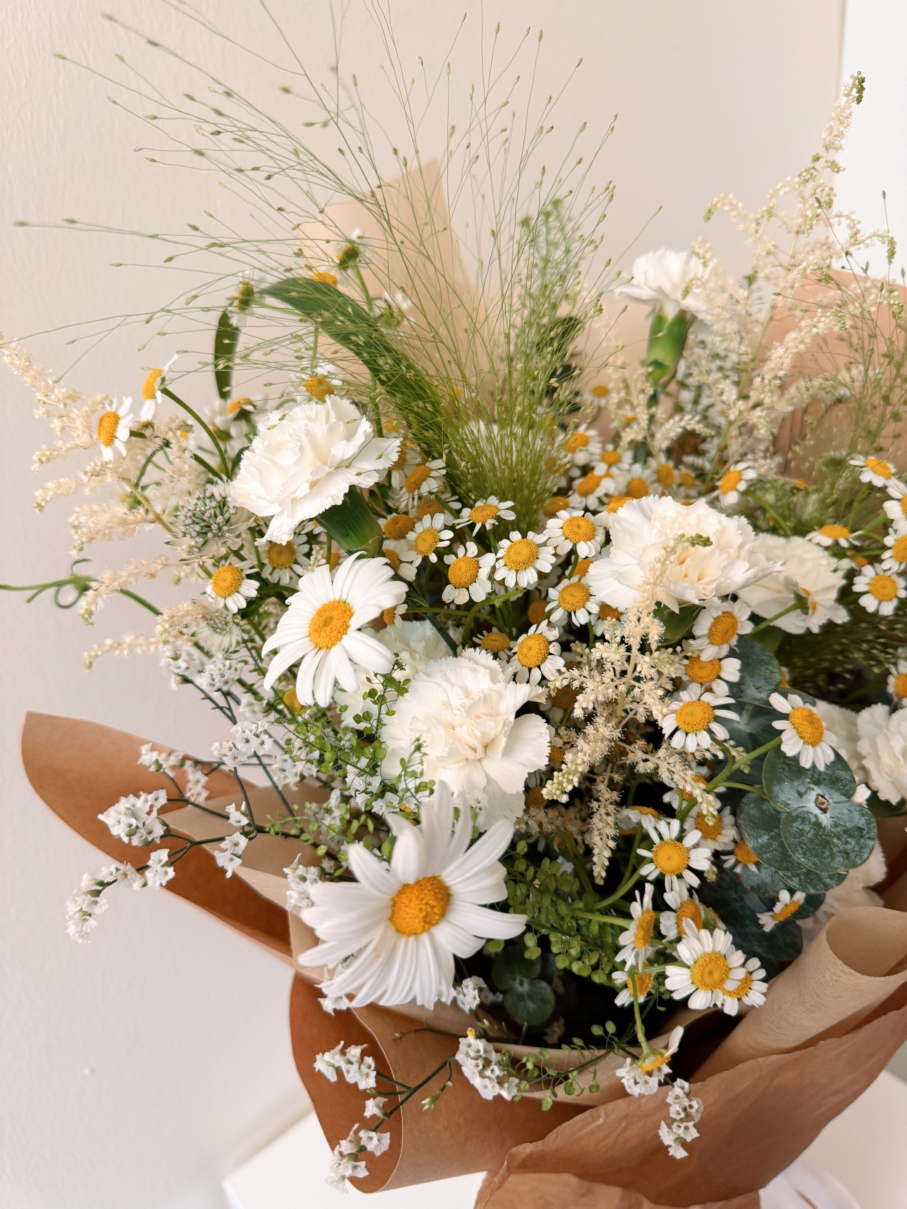 Wildflowers Musings featuring nature-inspired chamomile daisies with lots of textural foliage such as eucalyptus, wrapped in tissue paper and brown kraft paper crafted by Eden’s Ground.