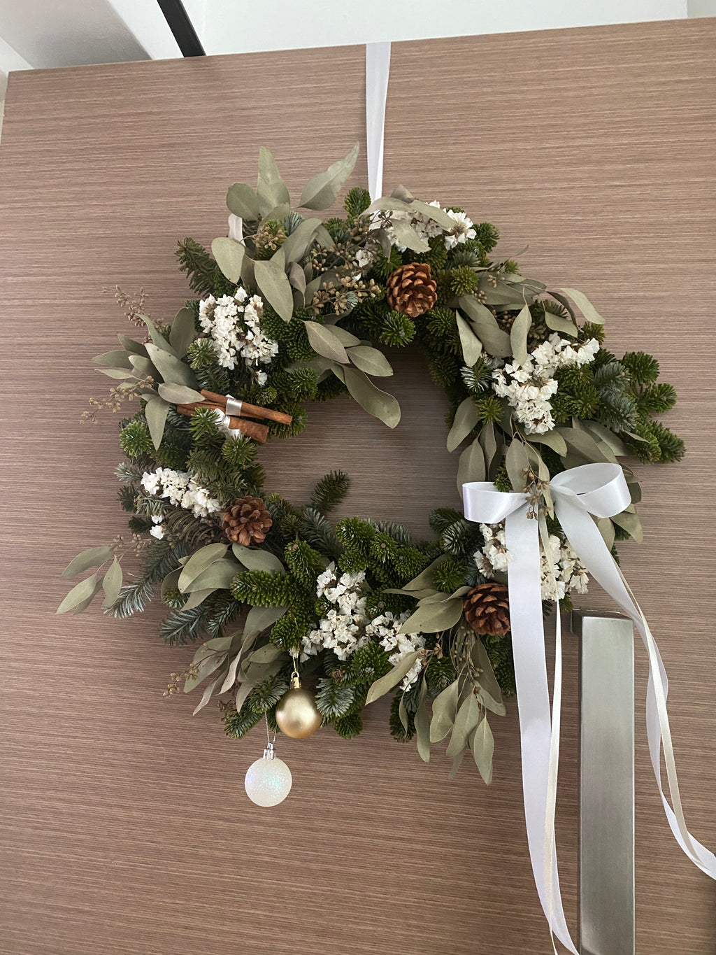 Fresh Christmas Wreath, decorated with baubles, ornaments, cotton, pinecones, cinnamon sticks and more by Eden's Ground, a Floral Design Studio in Singapore.