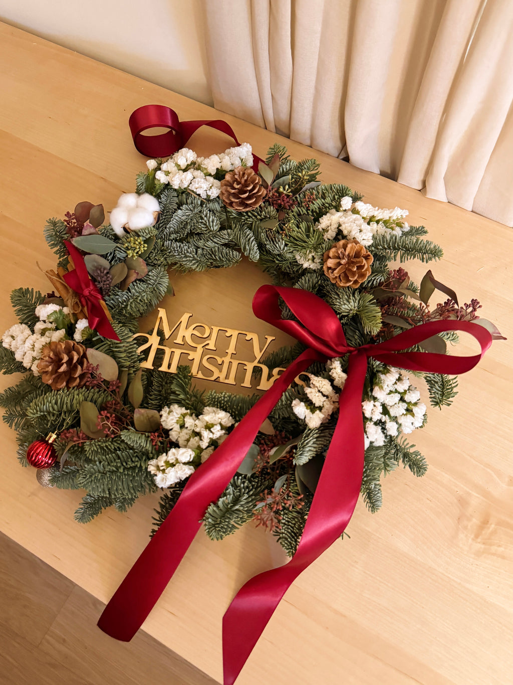 Fresh Christmas Wreath, decorated with baubles, ornaments, cotton, pinecones, cinnamon sticks and more by Eden's Ground, a Floral Design Studio in Singapore.