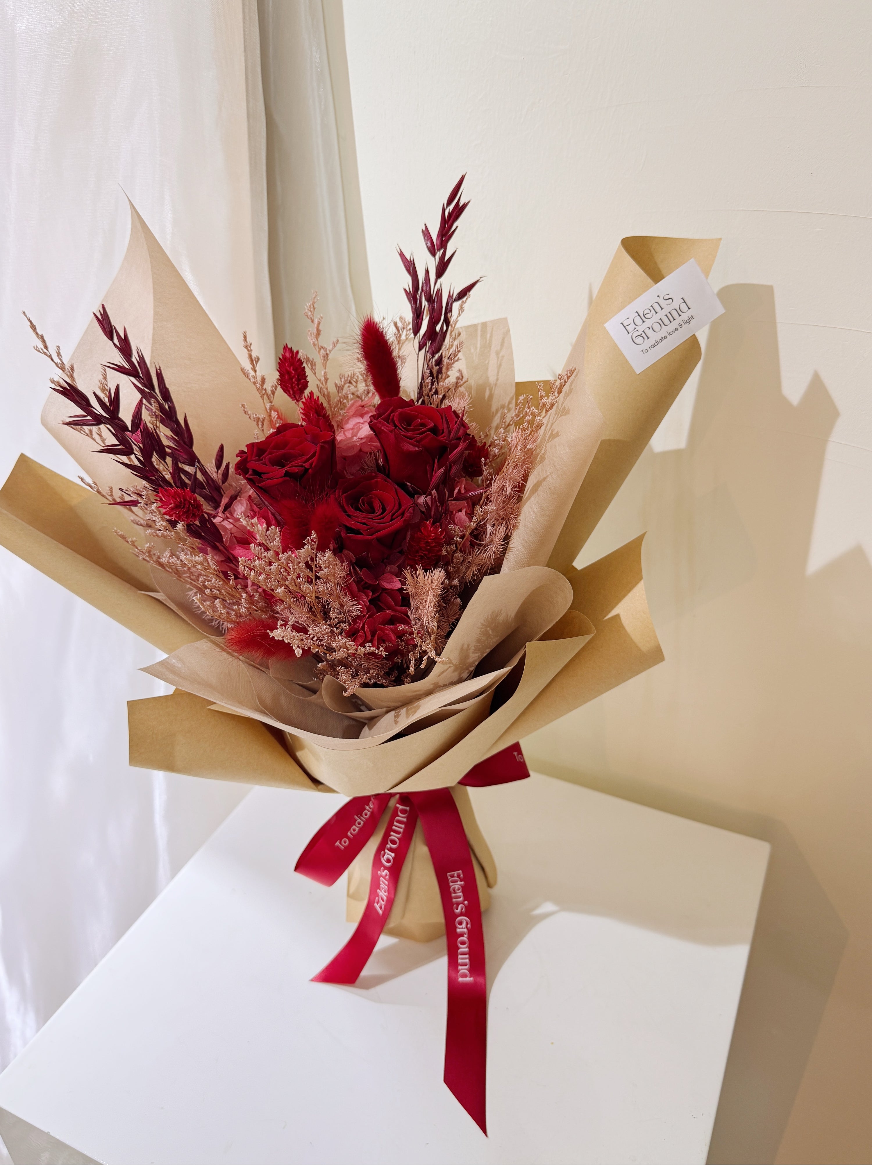 For Valentine's Day 2027, Eternal valentine bouquet made with all shades of red to symbolise deep love, surrounded by textural foliage, wrapped in tissue paper and kraft paper, crafted by Eden’s Ground. Delivered straight to your doorstep.