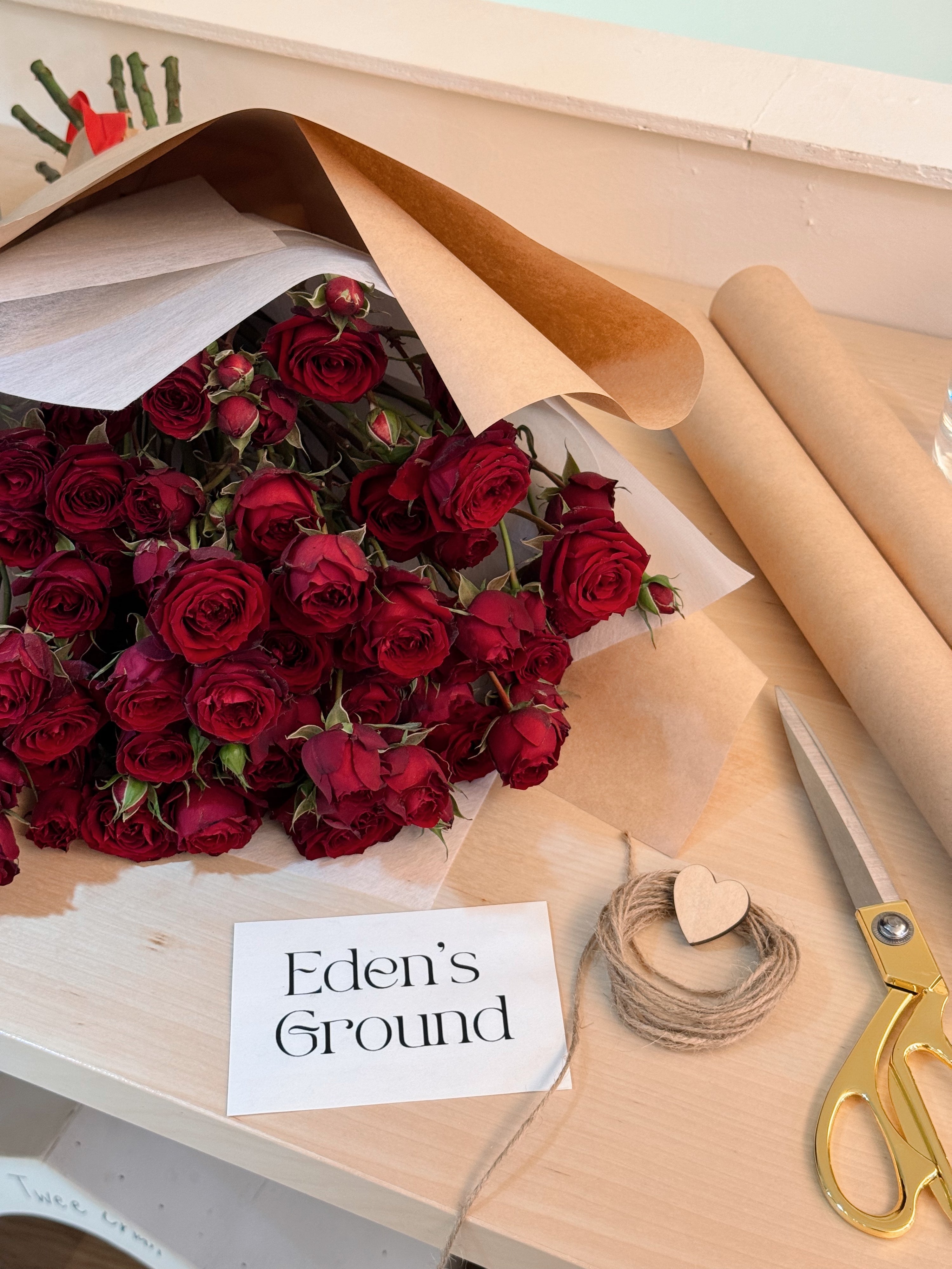 Lovin’ you so much more bouquet featuring red spray roses bouquet wrapped in white tissue paper and brown kraft paper crafted by Eden’s Ground.