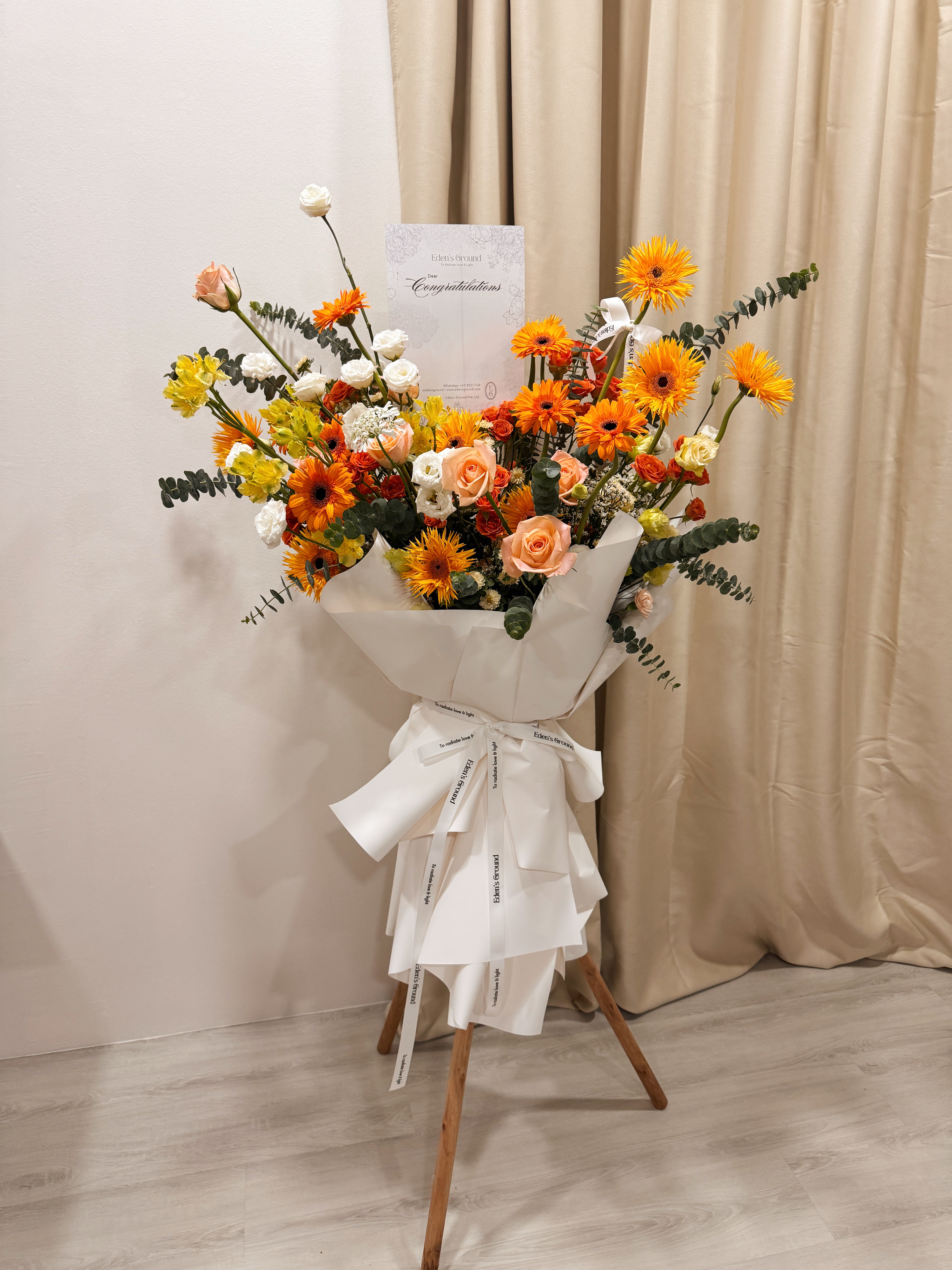 Warmest Congratulations, Fresh Flower Congratulatory Stand, featuring vibrant Roses, cheerful Gerbera, and the fresh touch of eucalyptus, crafted by Eden's Ground, a floral design boutique based in Singapore.