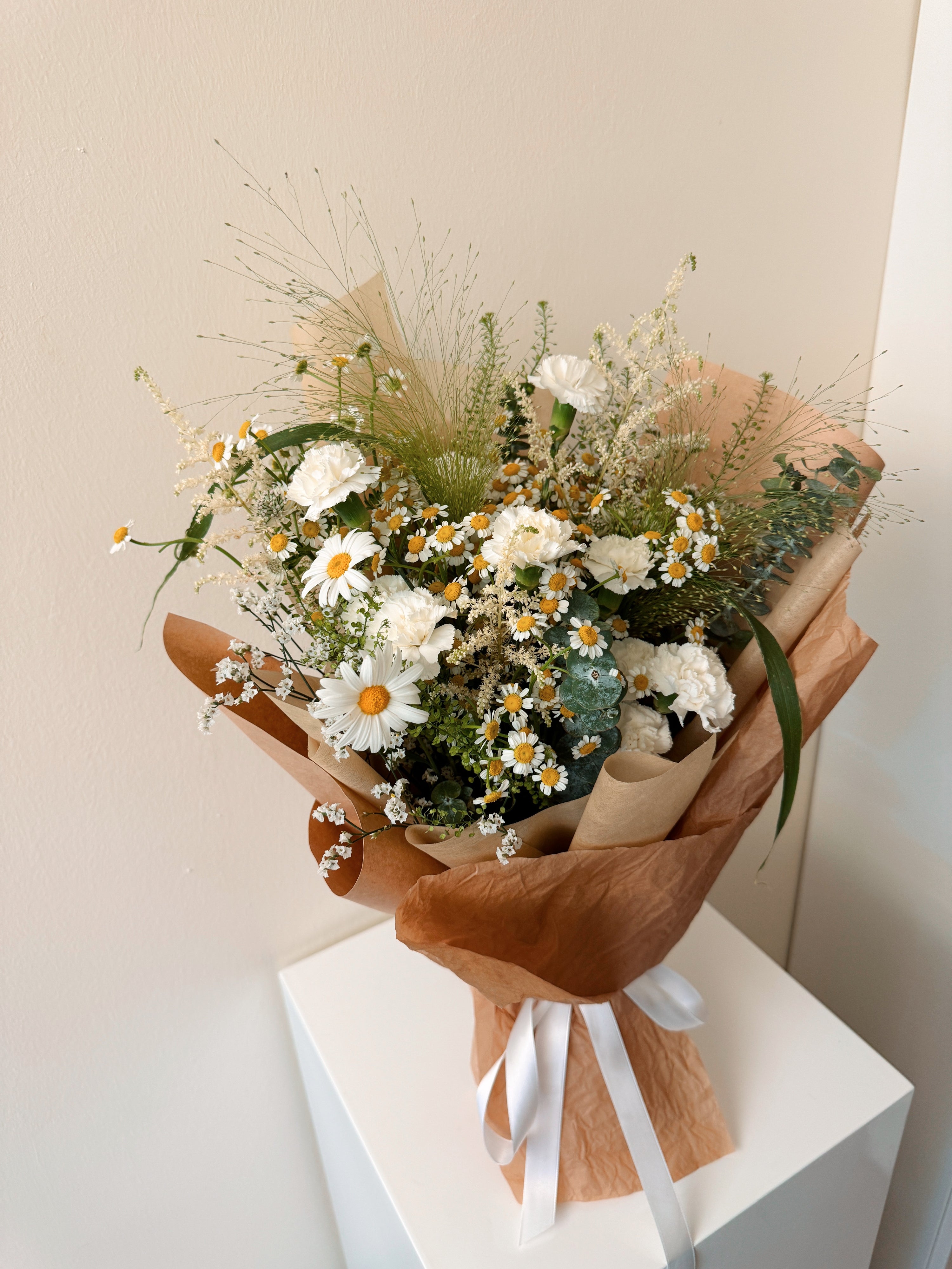Wildflowers Musings featuring nature-inspired chamomile daisies with lots of textural foliage such as eucalyptus, wrapped in tissue paper and brown kraft paper crafted by Eden’s Ground.
