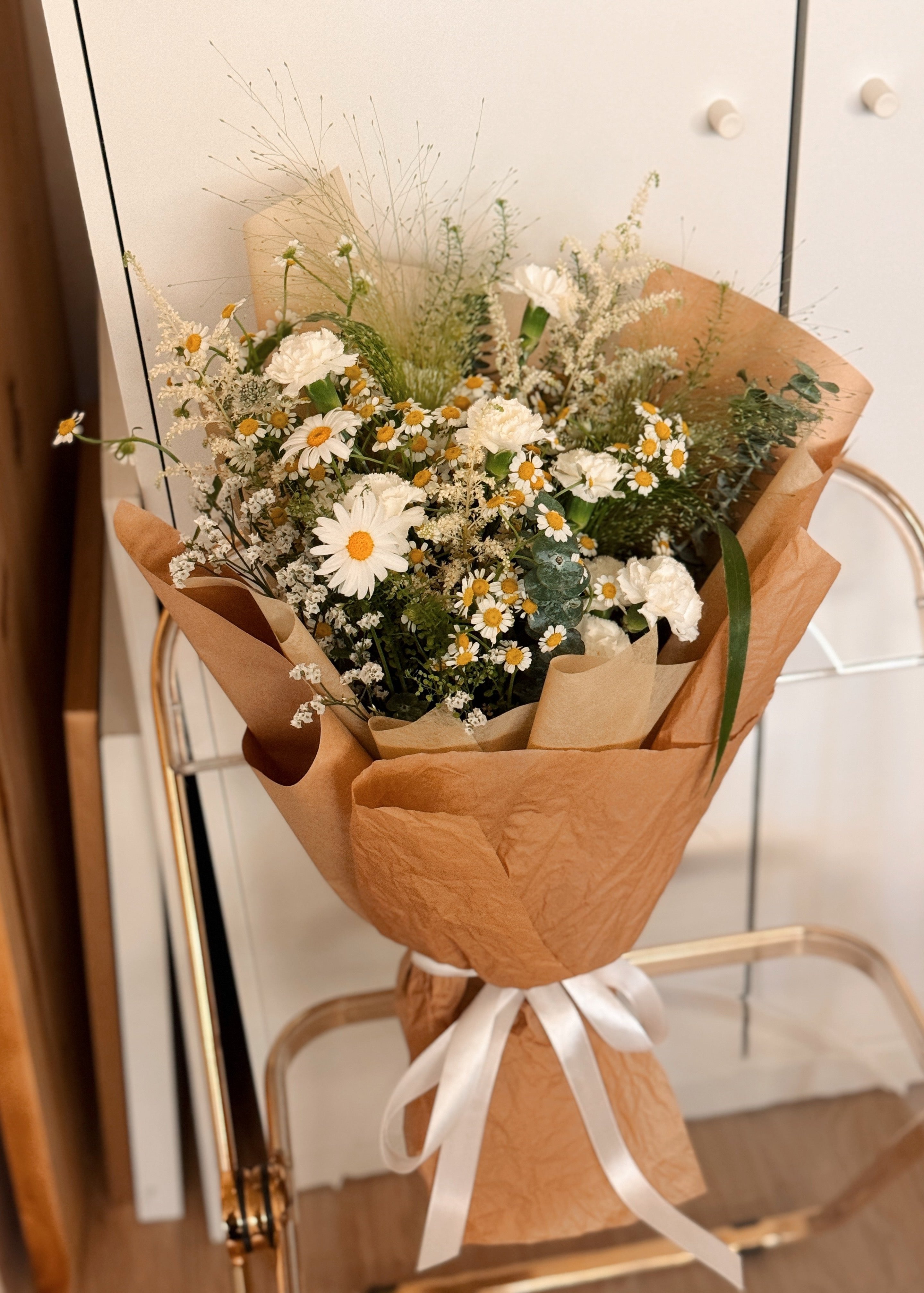 Wildflowers Musings featuring nature-inspired chamomile daisies with lots of textural foliage such as eucalyptus, wrapped in tissue paper and brown kraft paper crafted by Eden’s Ground.